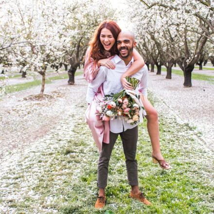 couple in love piggyback in almond trees