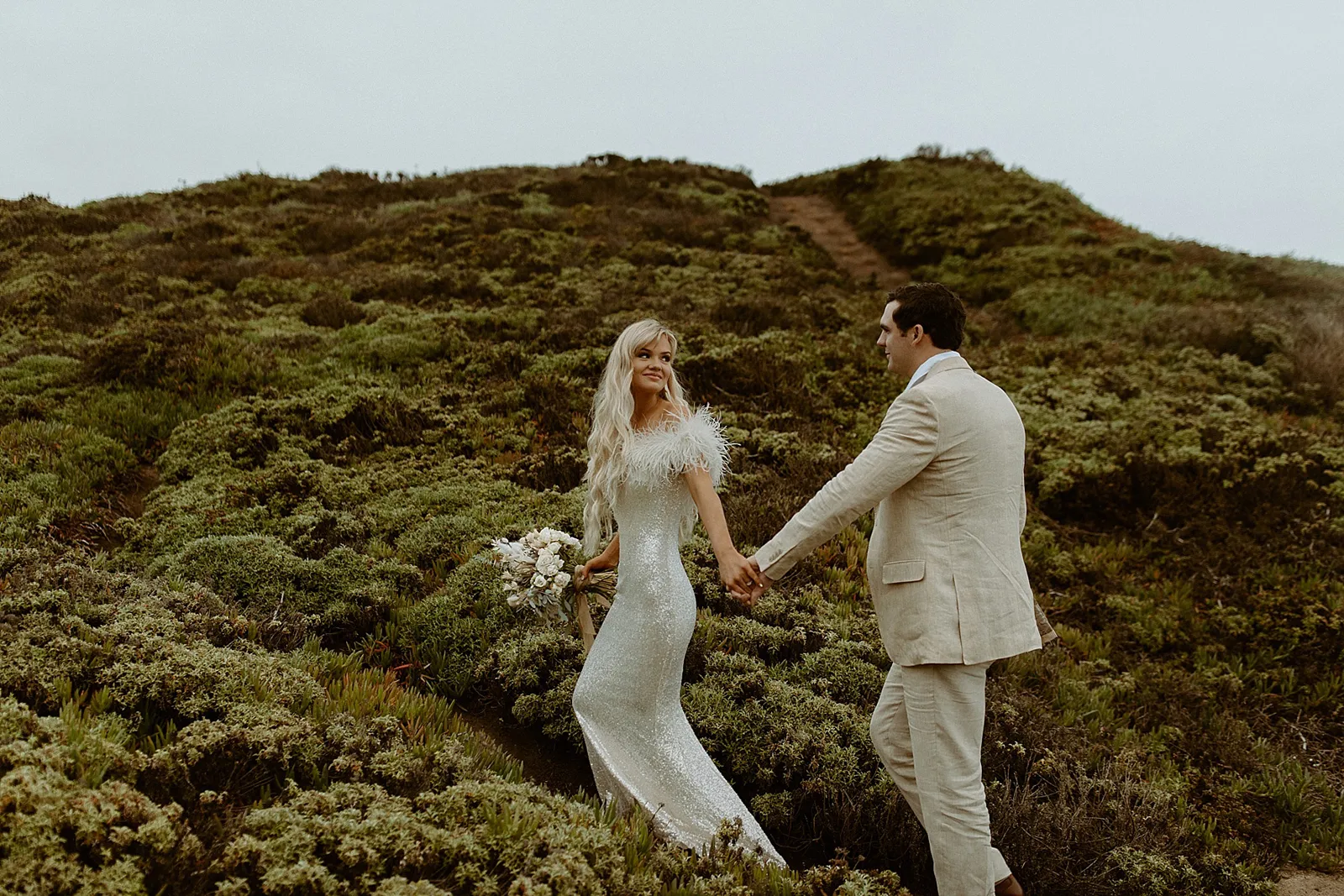 newlyweds walking on cliffside