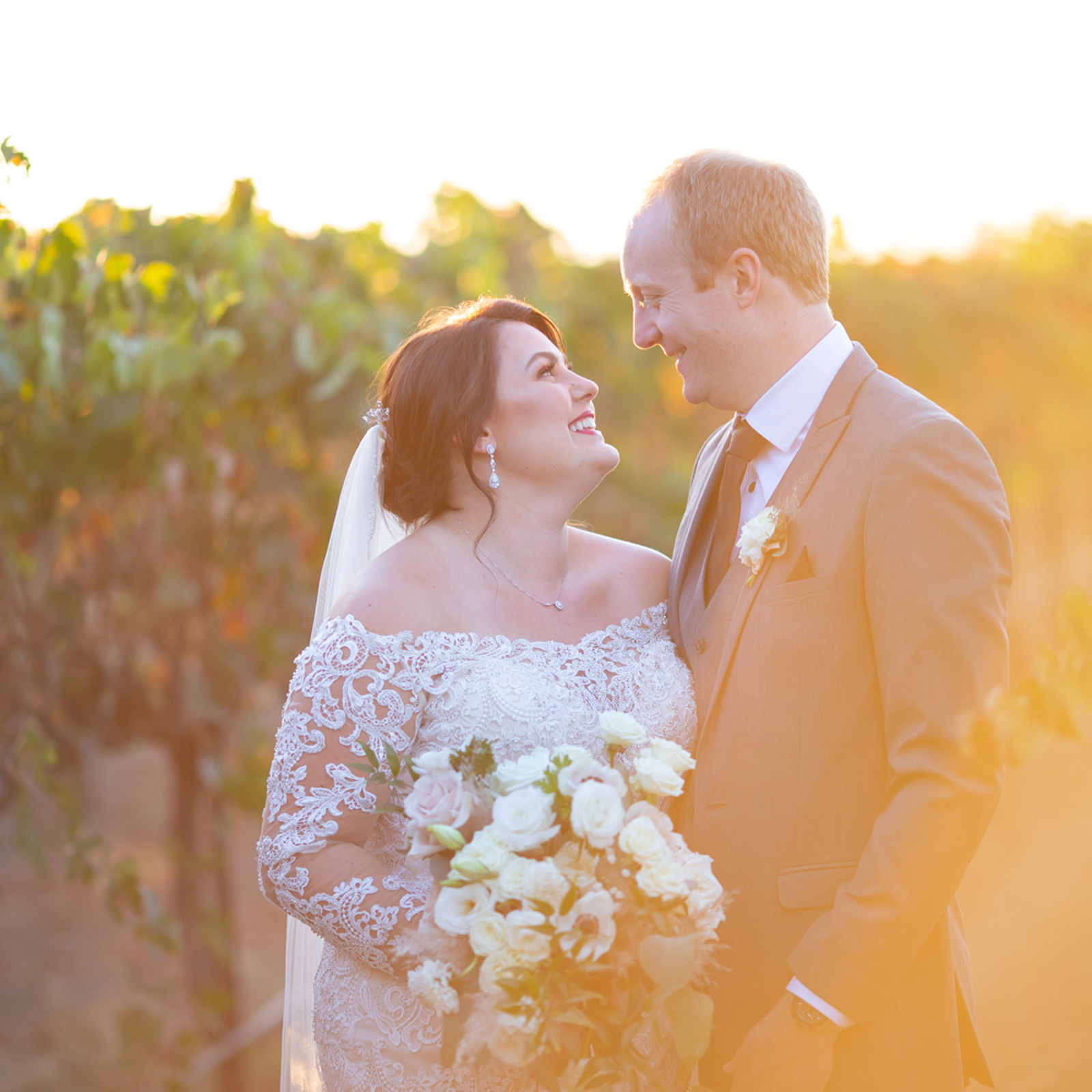 Bride and groom take photos during sunset at vineyard