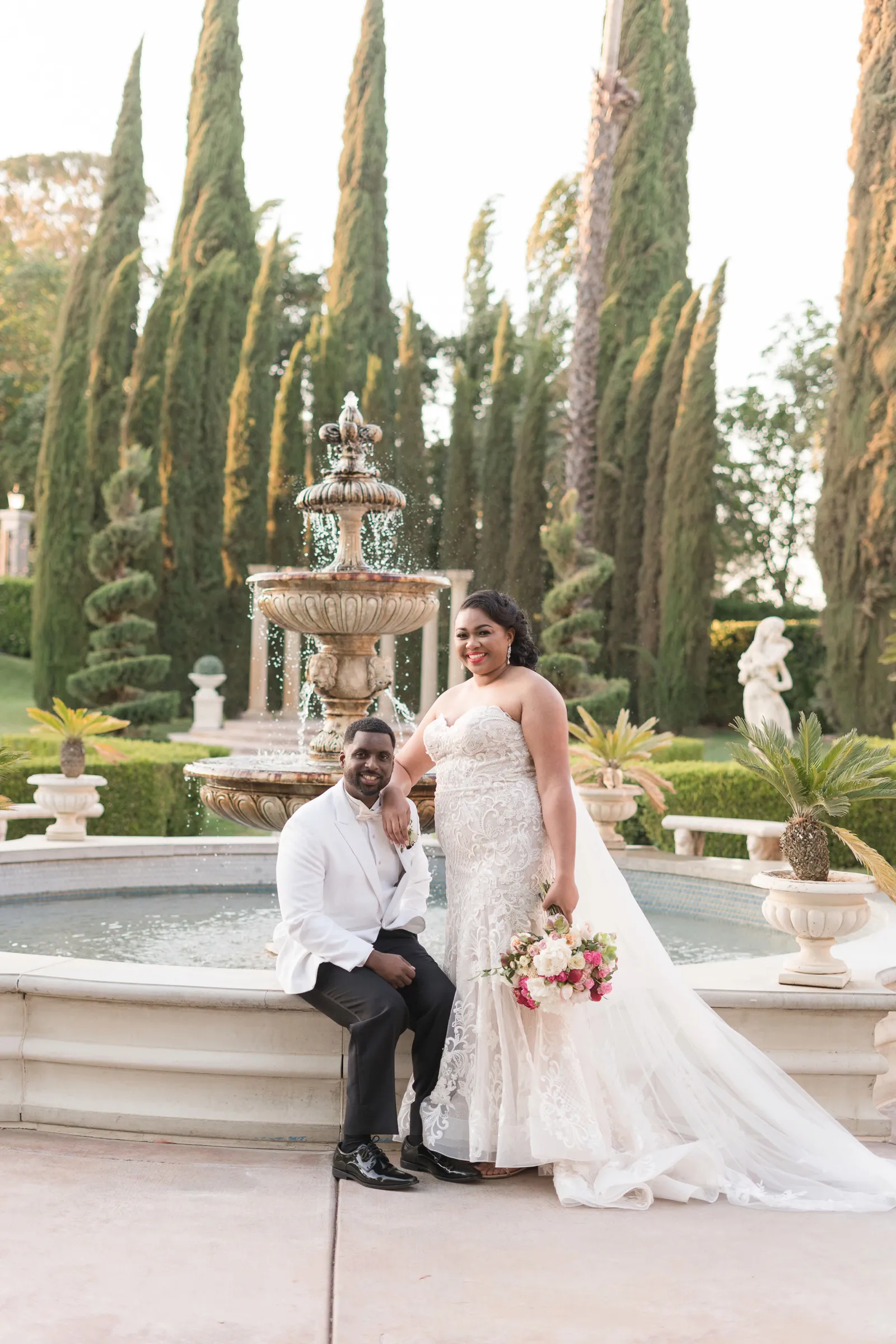 Newlyweds posing by fountain