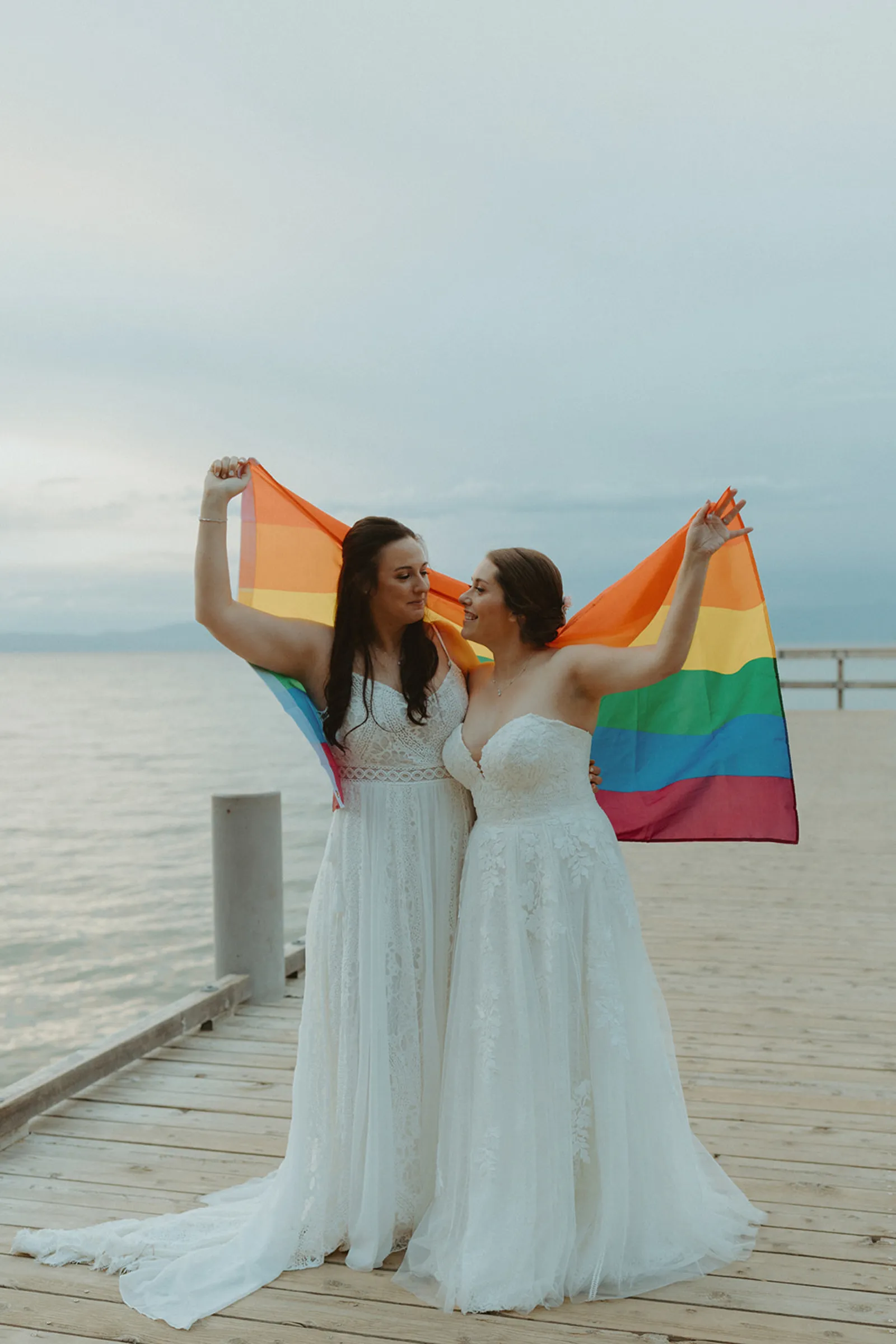 The newlyweds holding a pride flag near the lake