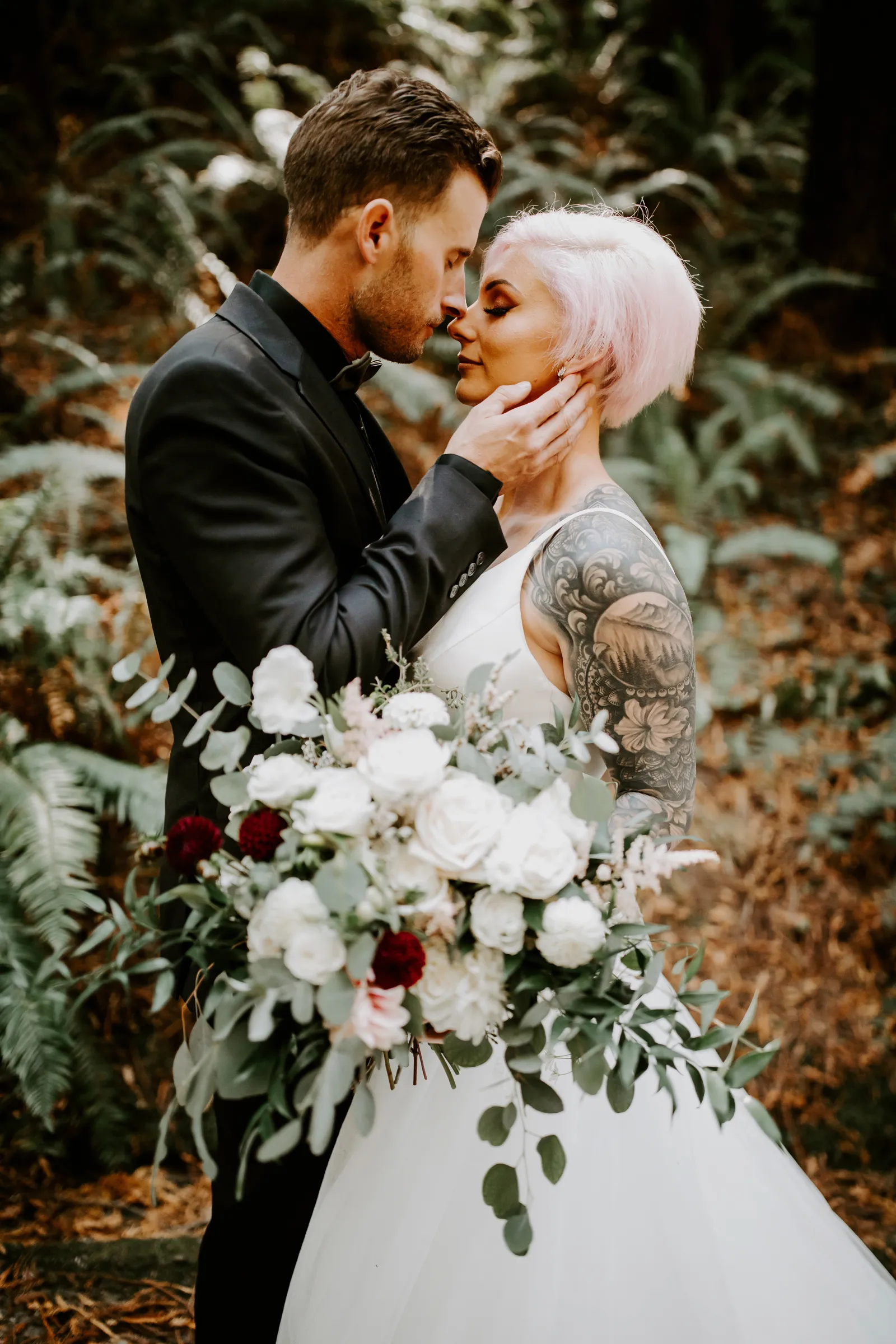 Groom about to kiss bride in the forest.