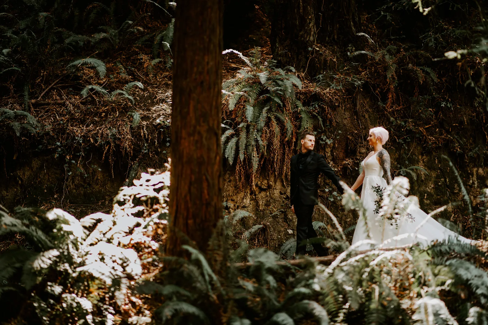 Bride and groom walking through forest