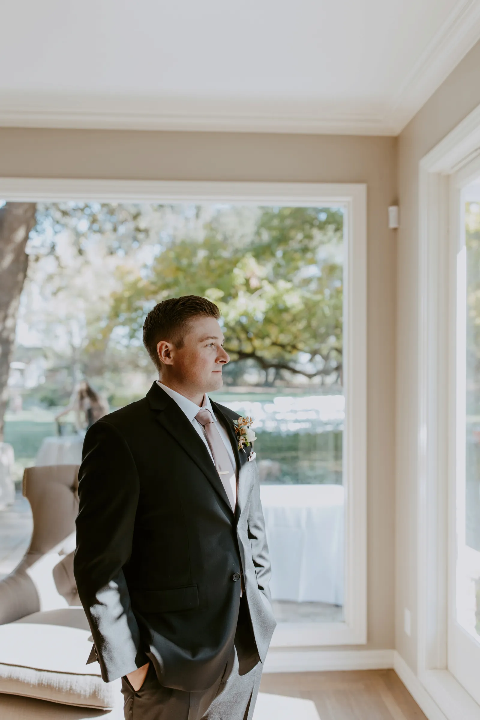 Groom smiling and looking out the window on his wedding day