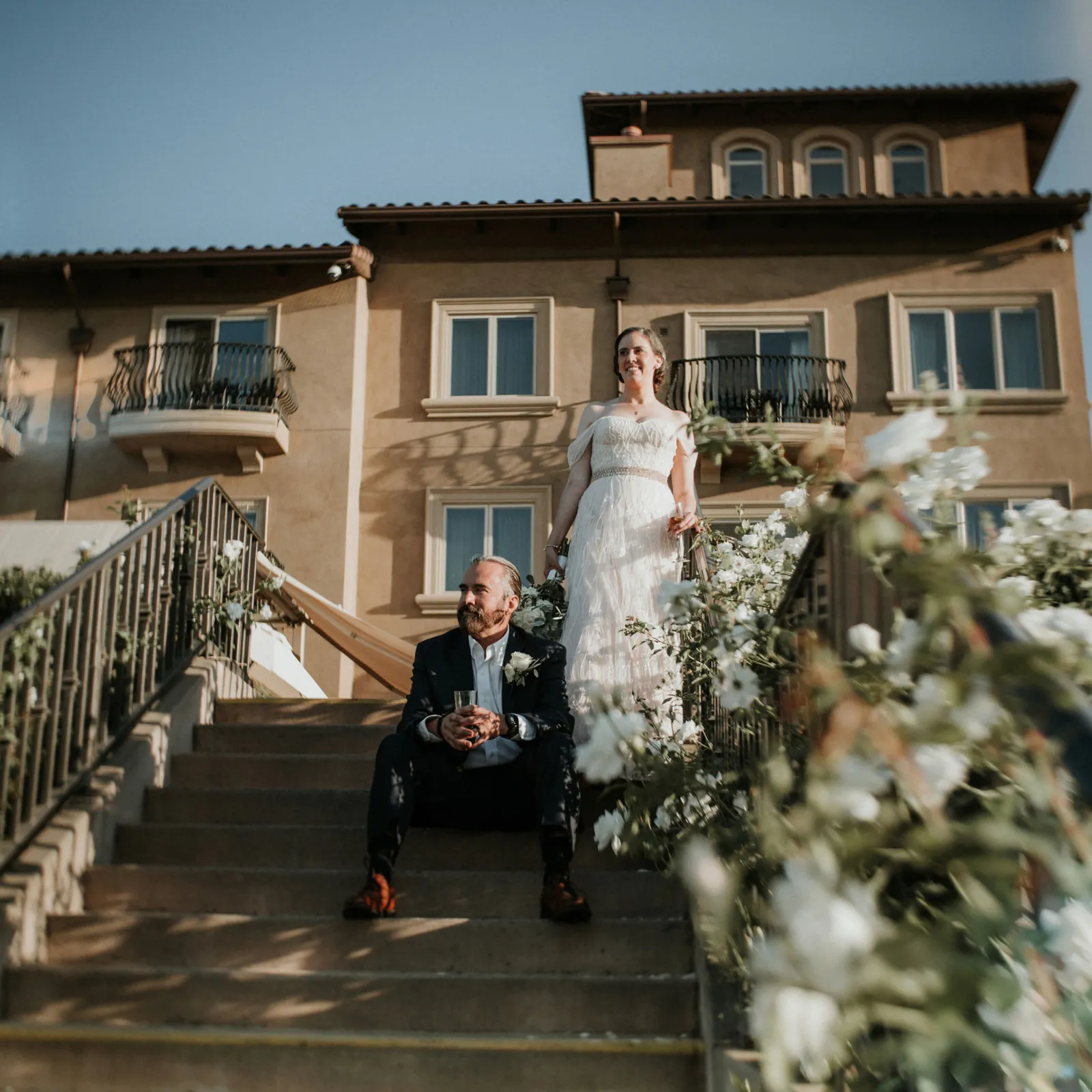 Bride and groom posing on stairs by their venue.