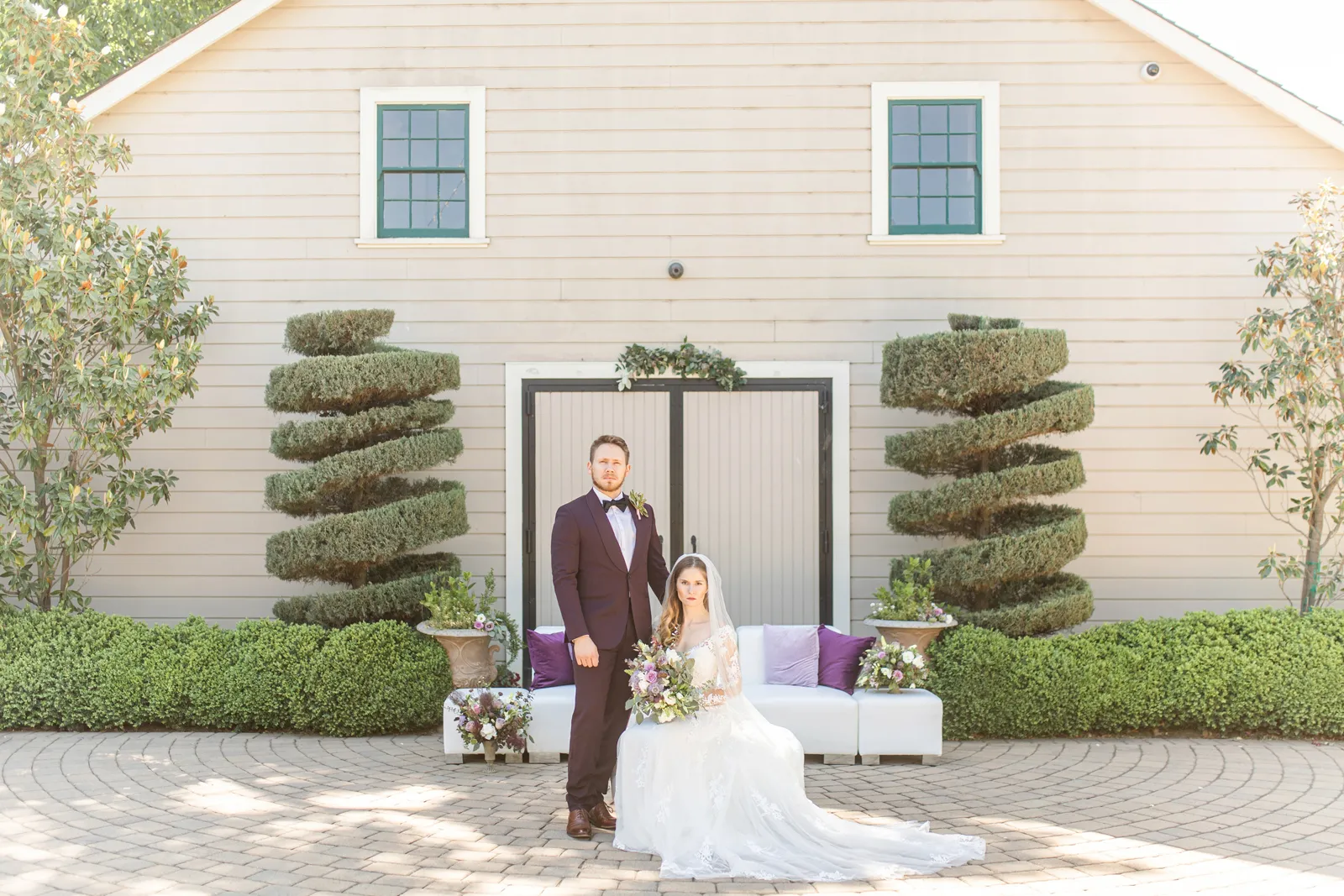 Bride and groom posing in front of a tan house