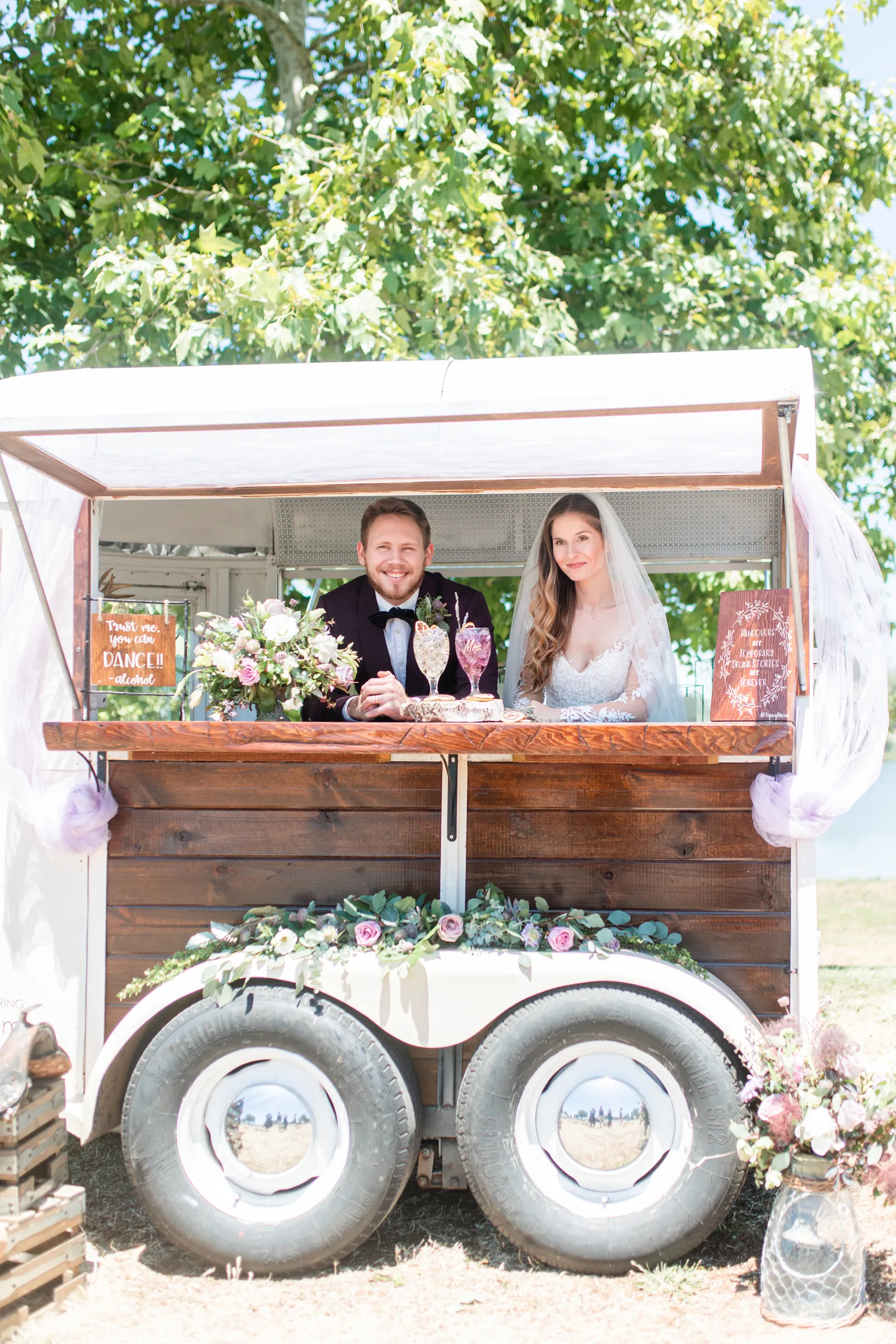 Bride and Groom smiling at camera inside of a moving bar cart.