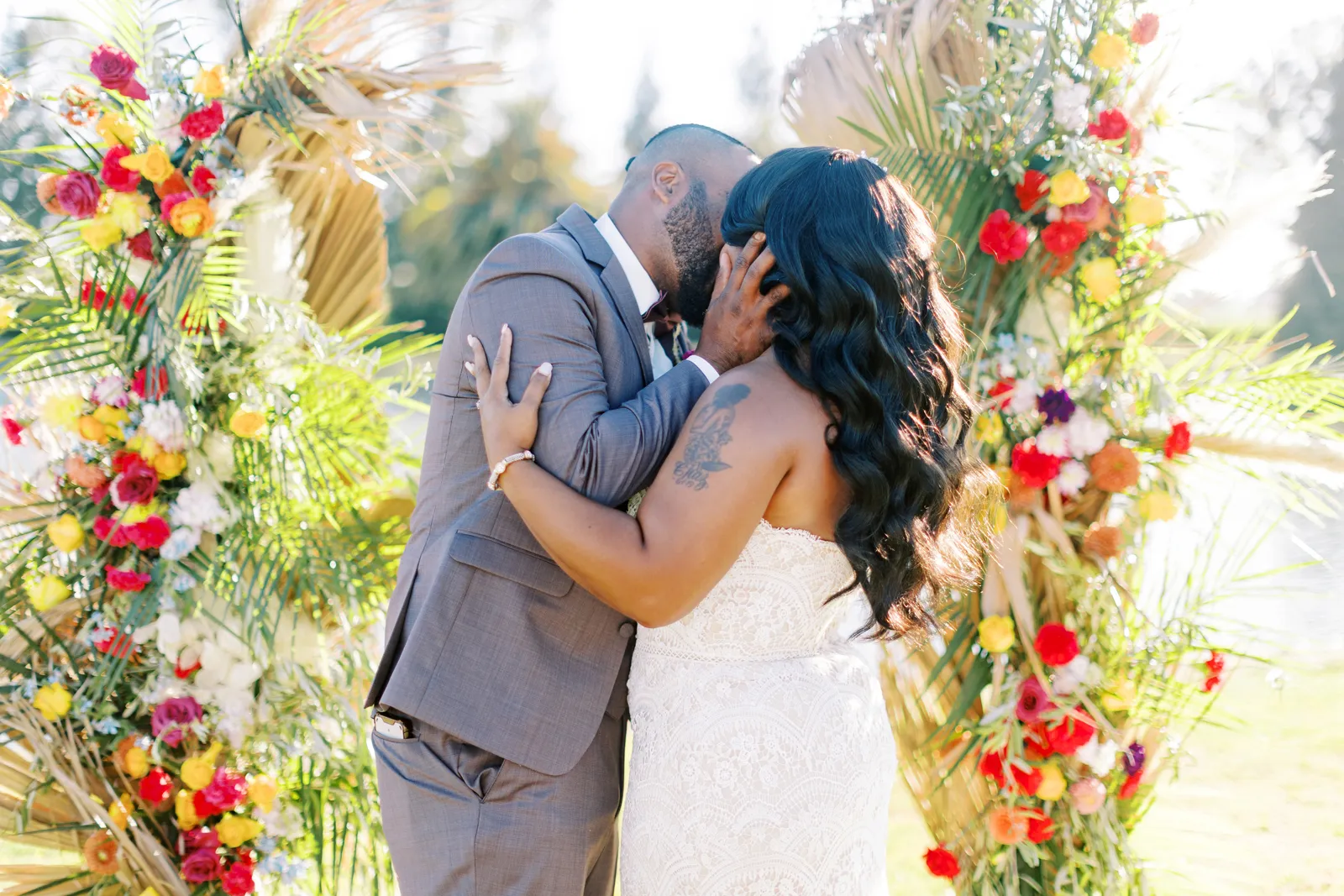 Bride and groom kissing in front of a flower altar