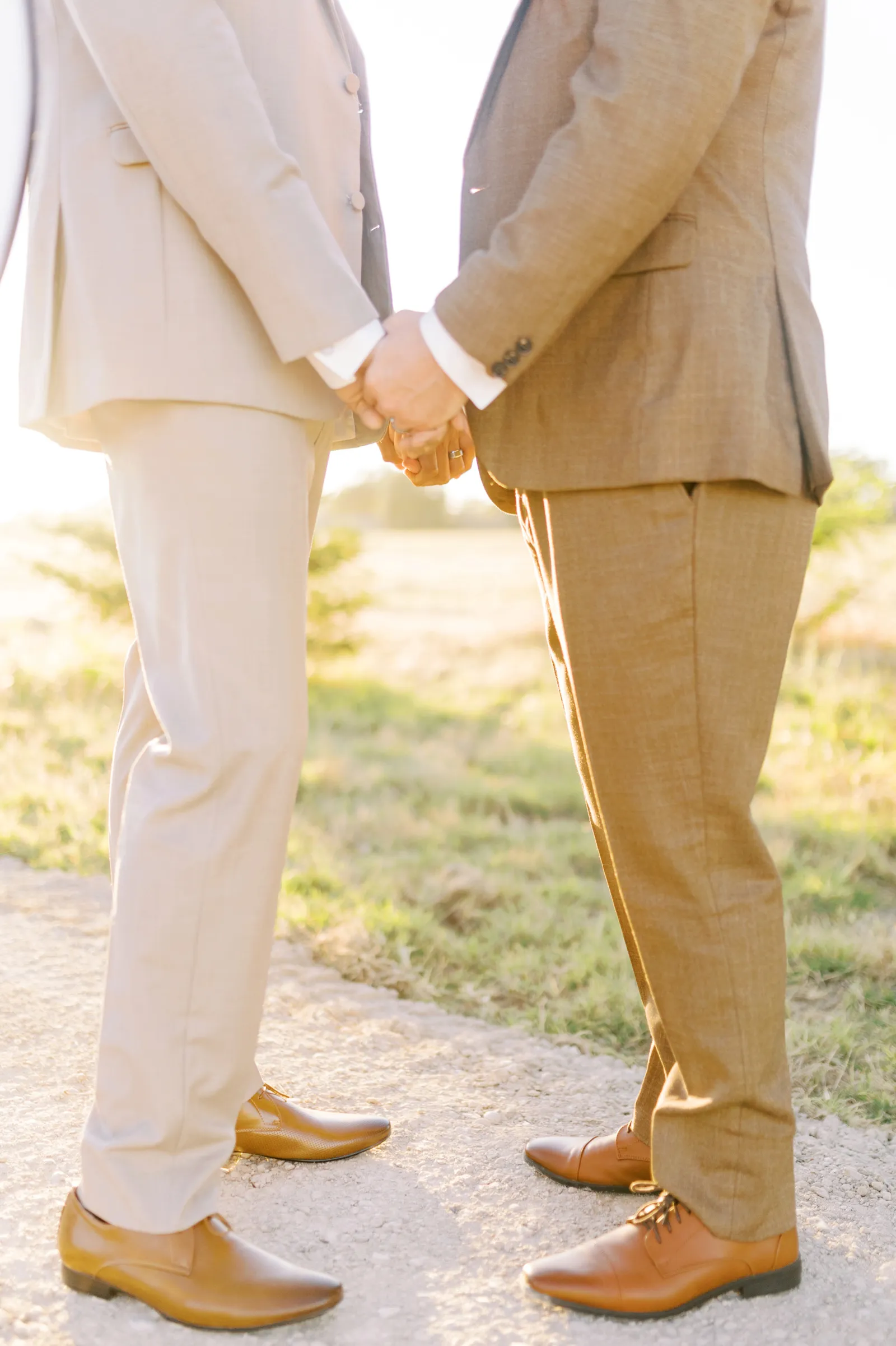 Grooms holding hands in the sunset