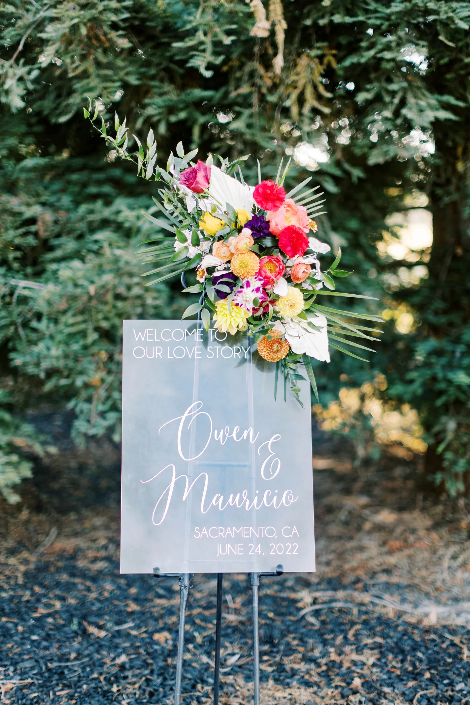 Welcome sign with pink, white, orange, and red flowers on it welcoming guests.