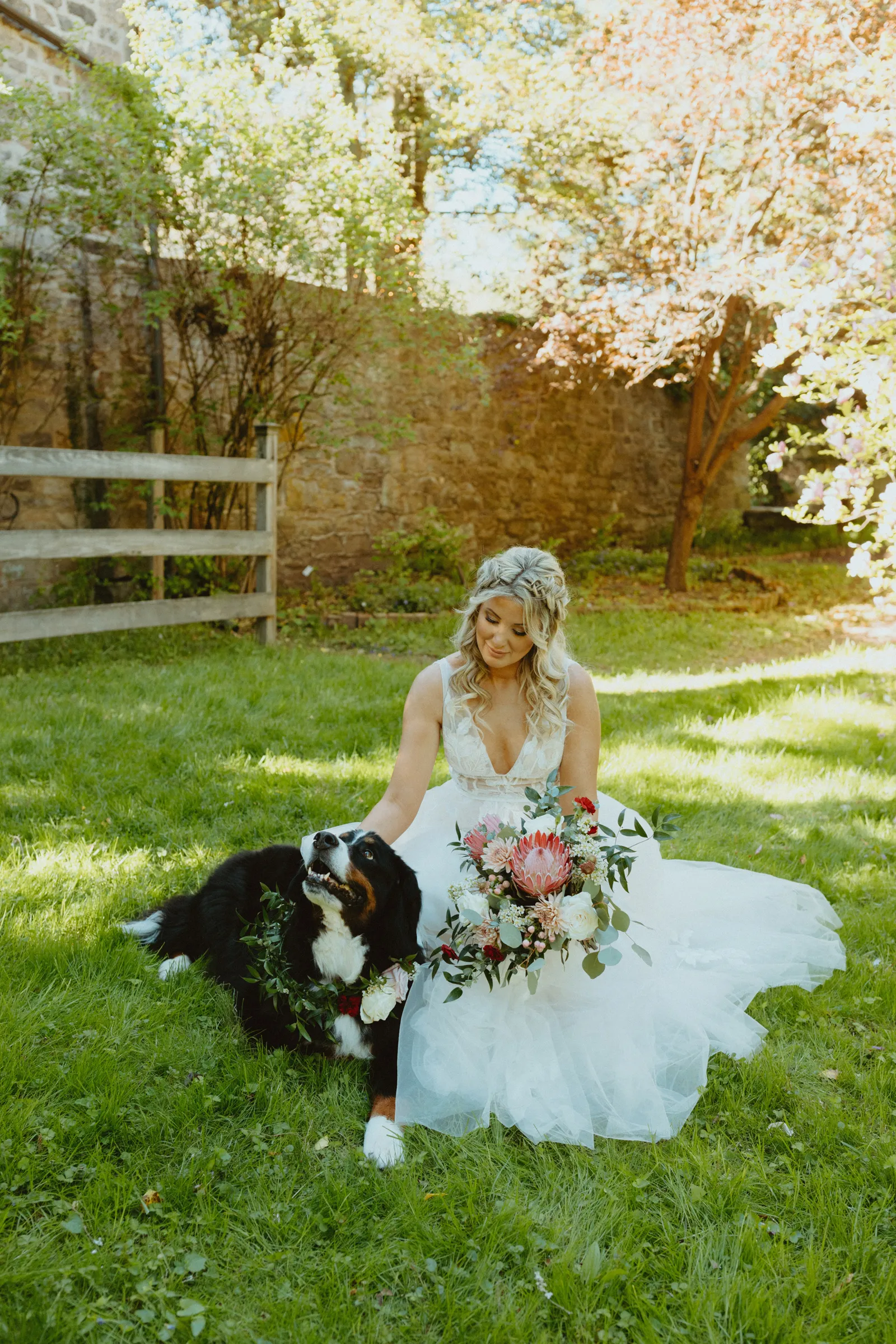 Bride smiling on the ground with her mountain dog.