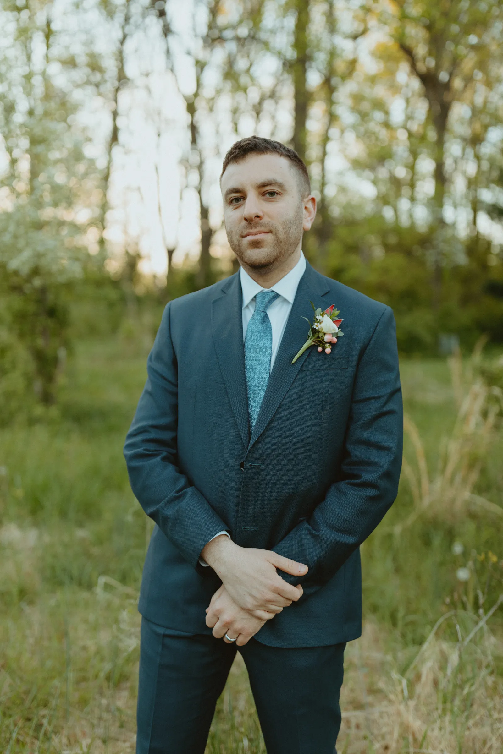 Groom posing and smiling outside.