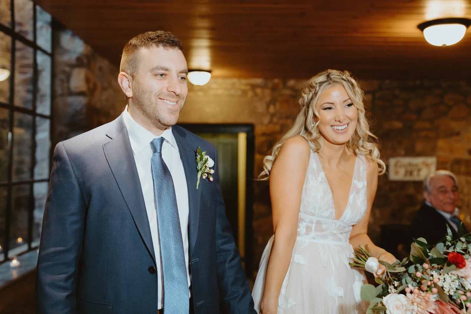 Newlyweds smiling and holding hands as they walk into their reception.