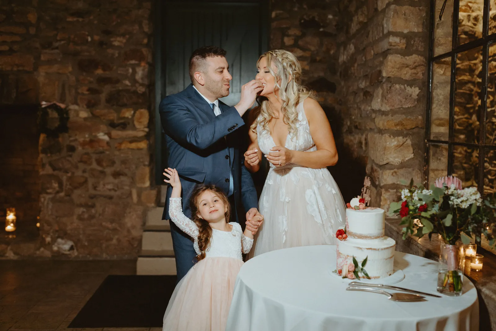 Groom feeding his wife a piece of their wedding cake.