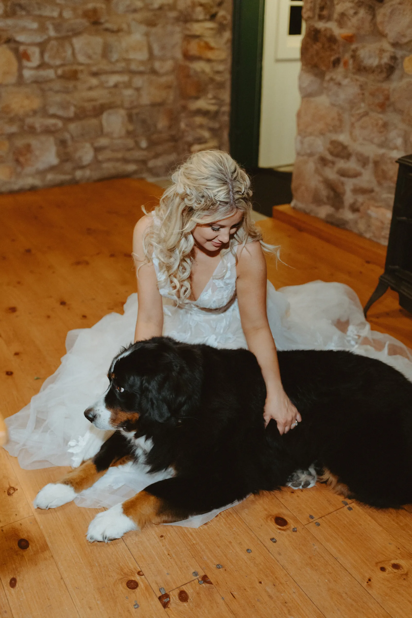 Bride sitting on the floor with her Bernese Mountain Dog.