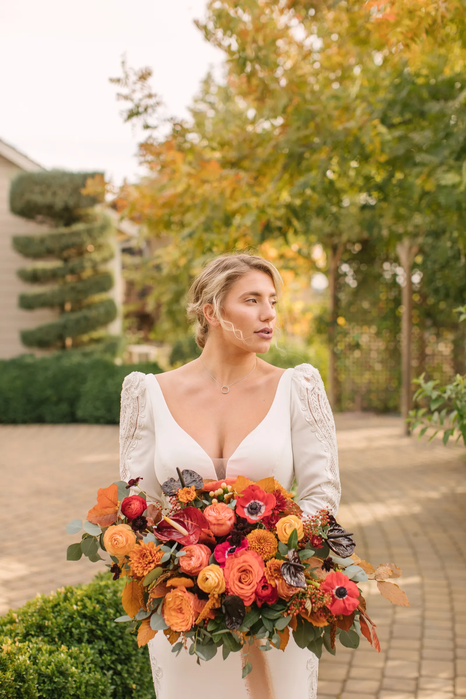 Bride holding warm-colored flowers and staring sideways