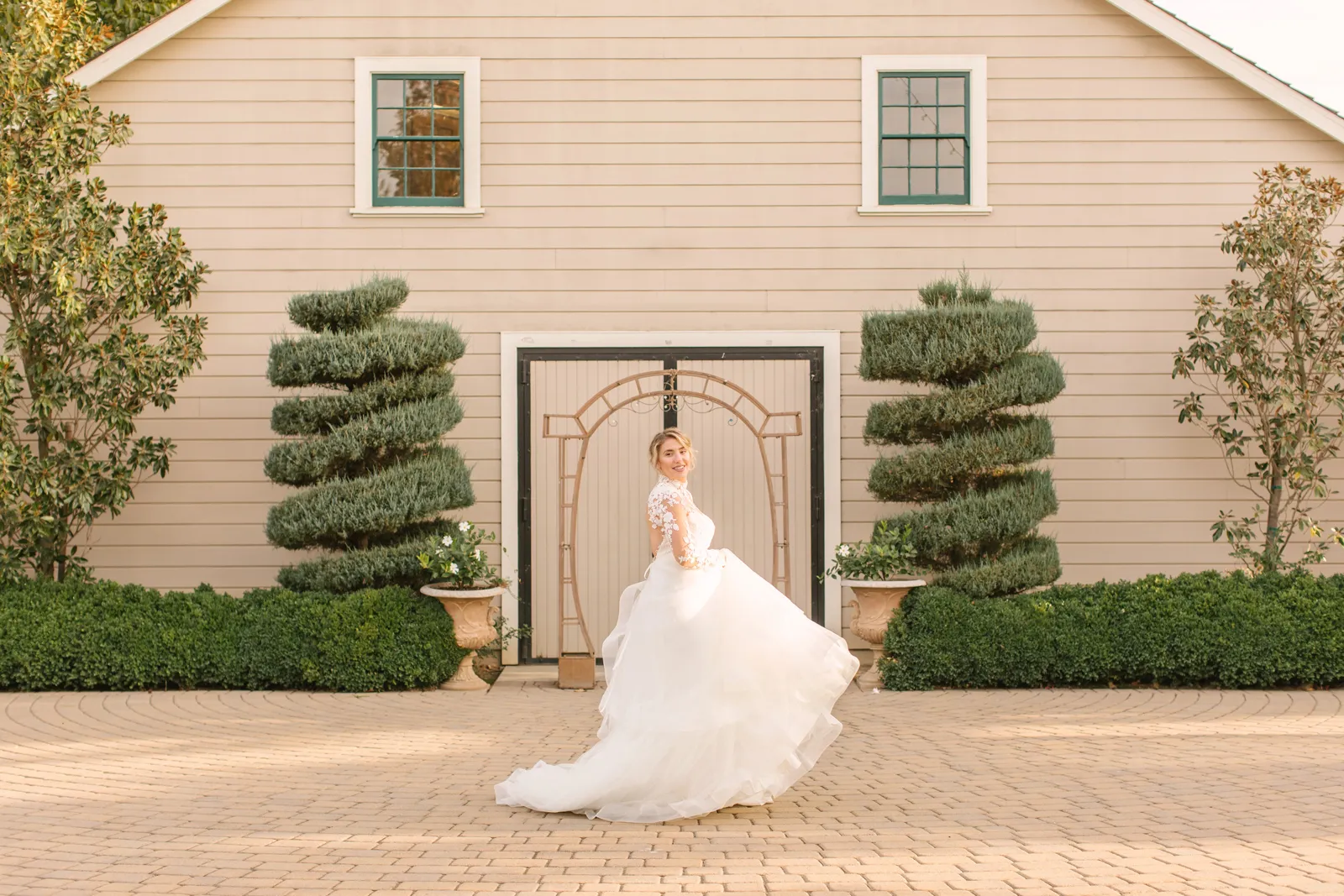 Bride swishing her dress in between two hedges at Scribner Bend Vineyards.