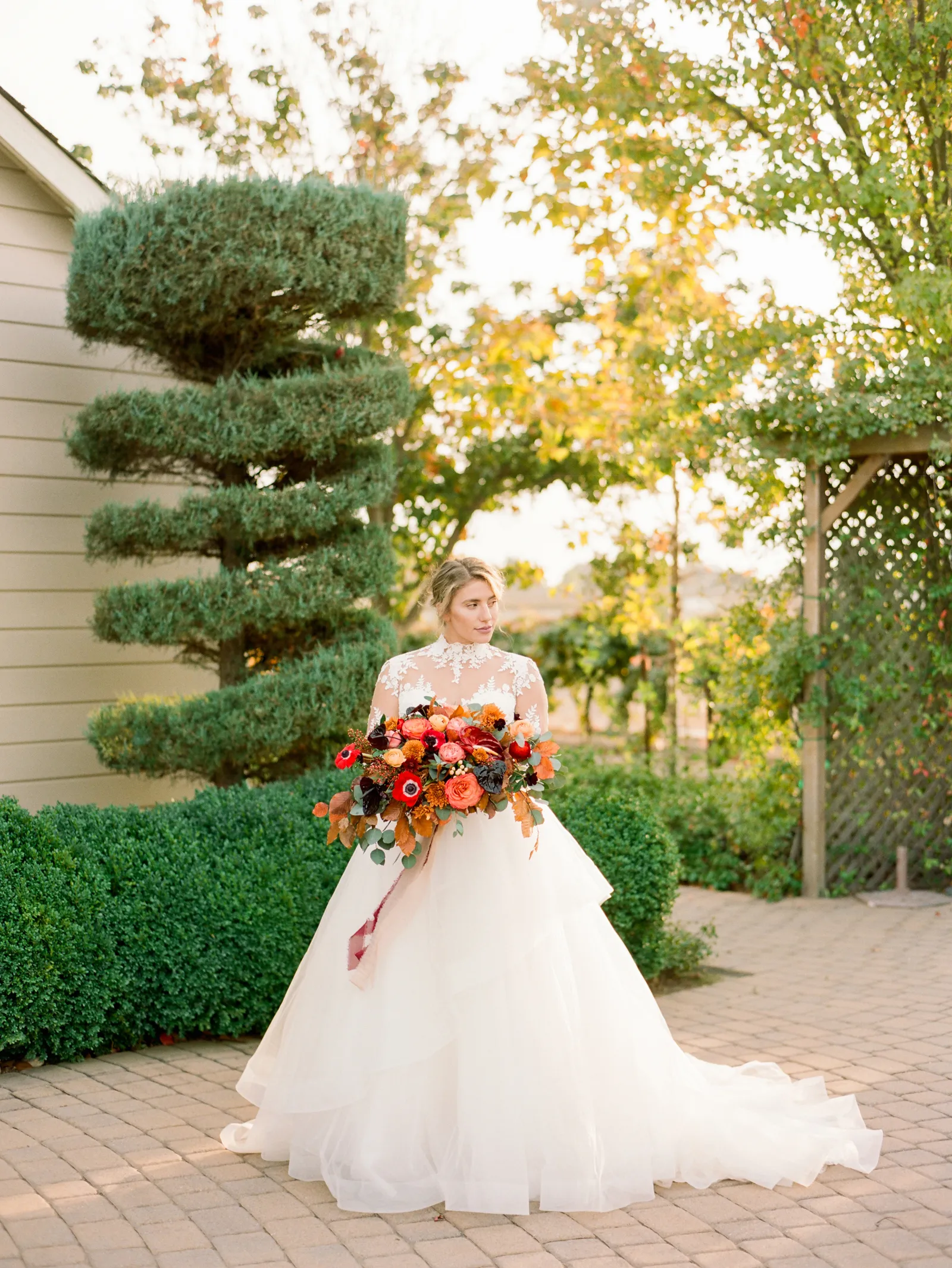 Full shot of the bride holding a bouquet in front of some hedges at Scribner Bend Vineyards.