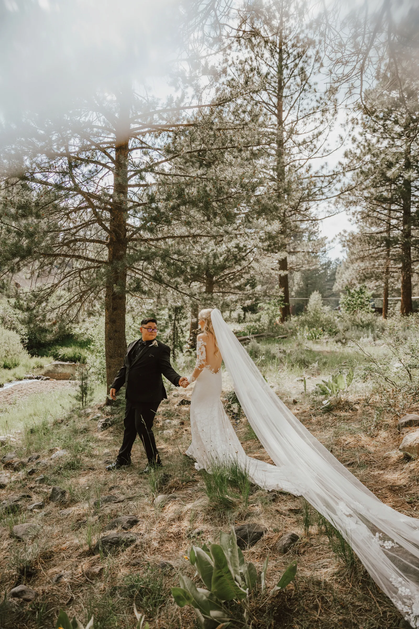 Groom leading bride through the woods.