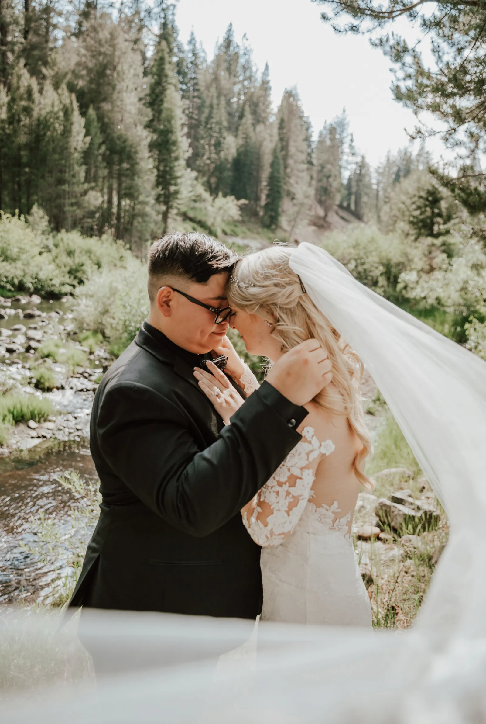 Groom holding bride's face as her veil sways