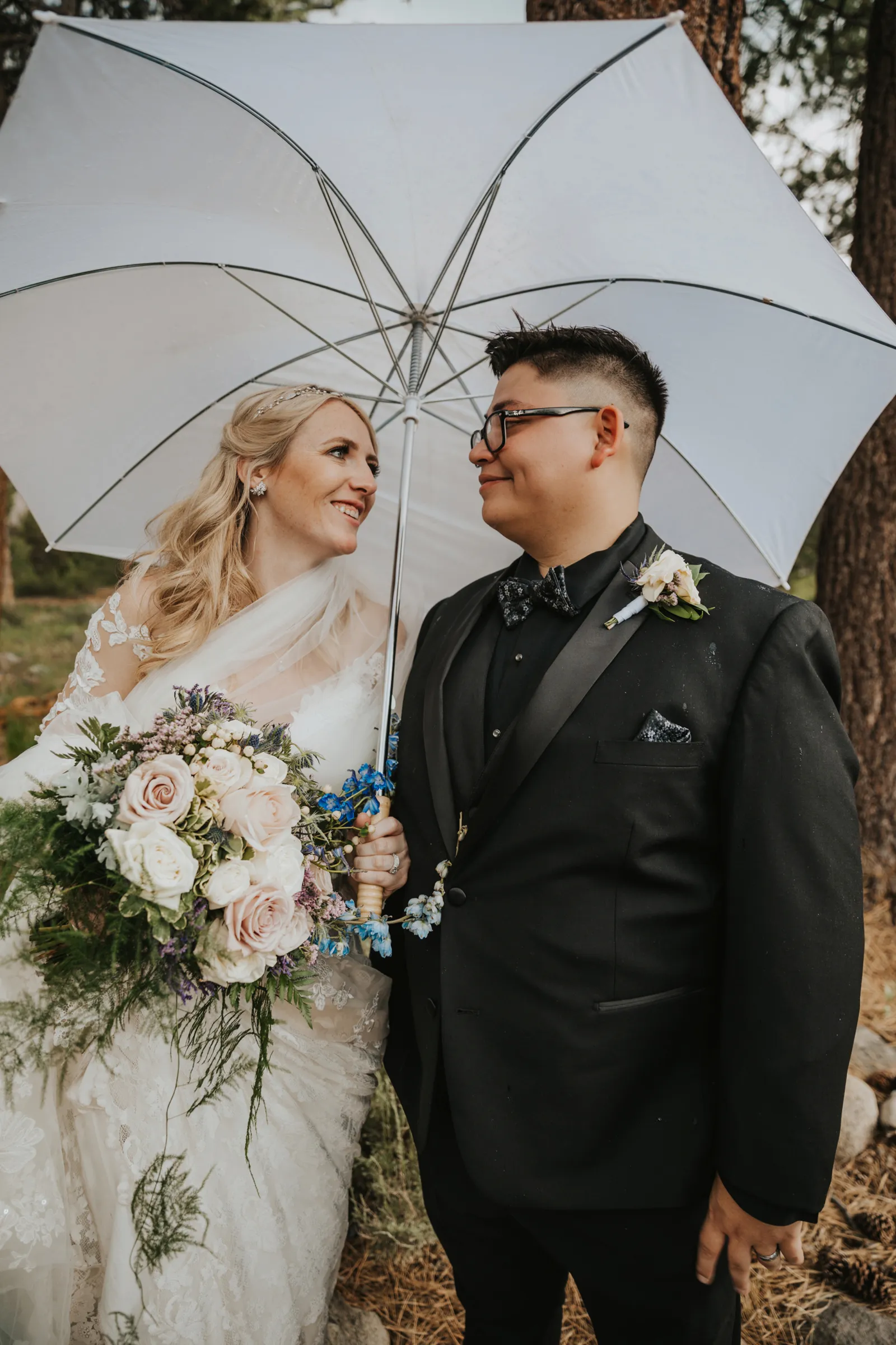 Bride carrying an umbrella and smiling at her husband.