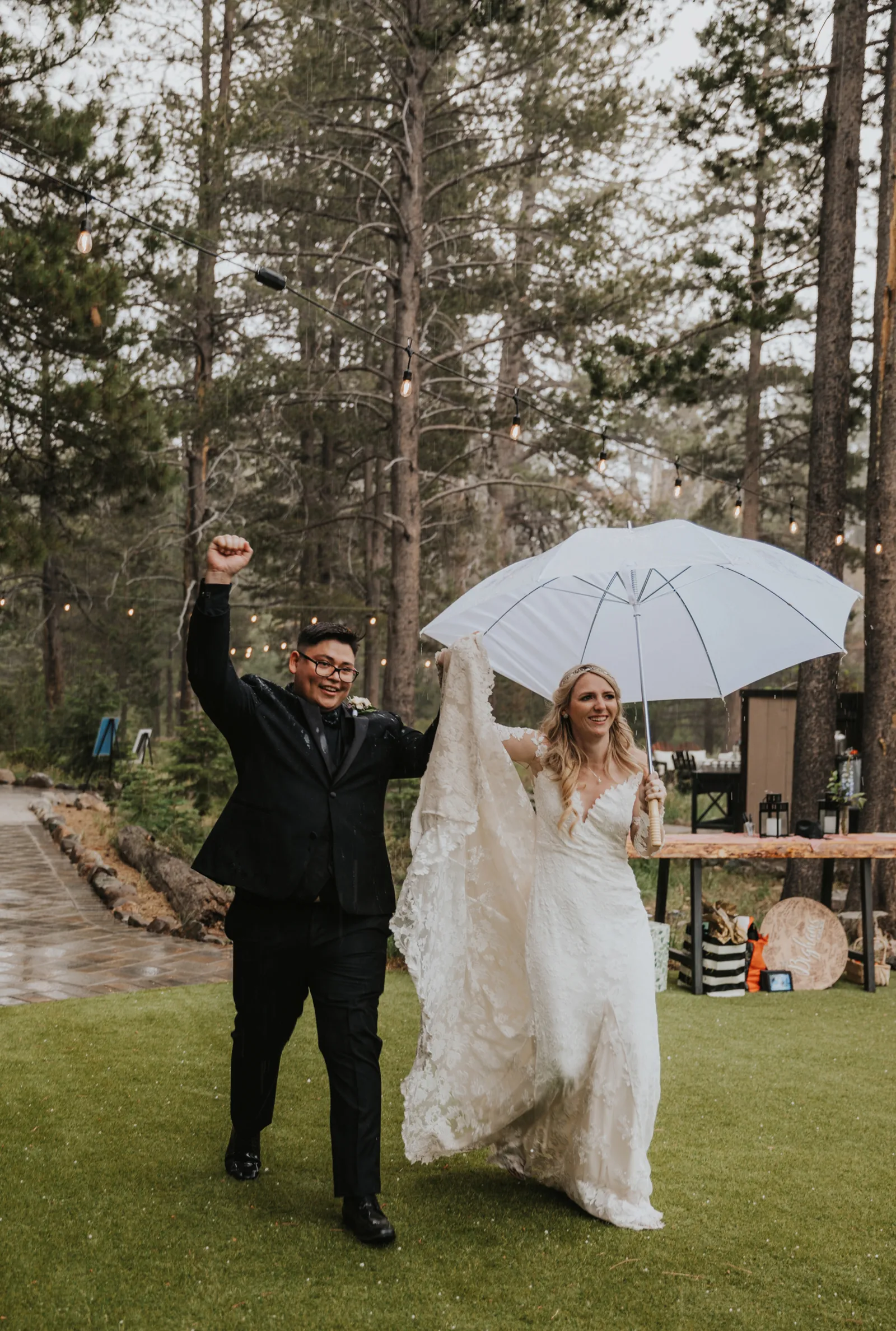 Bride and husband holding an umbrella, walking into their reception.