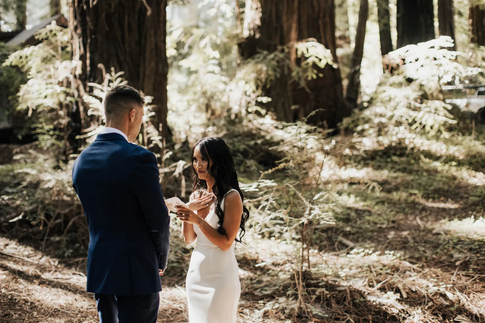 Bride smiling as her groom reads his vows.