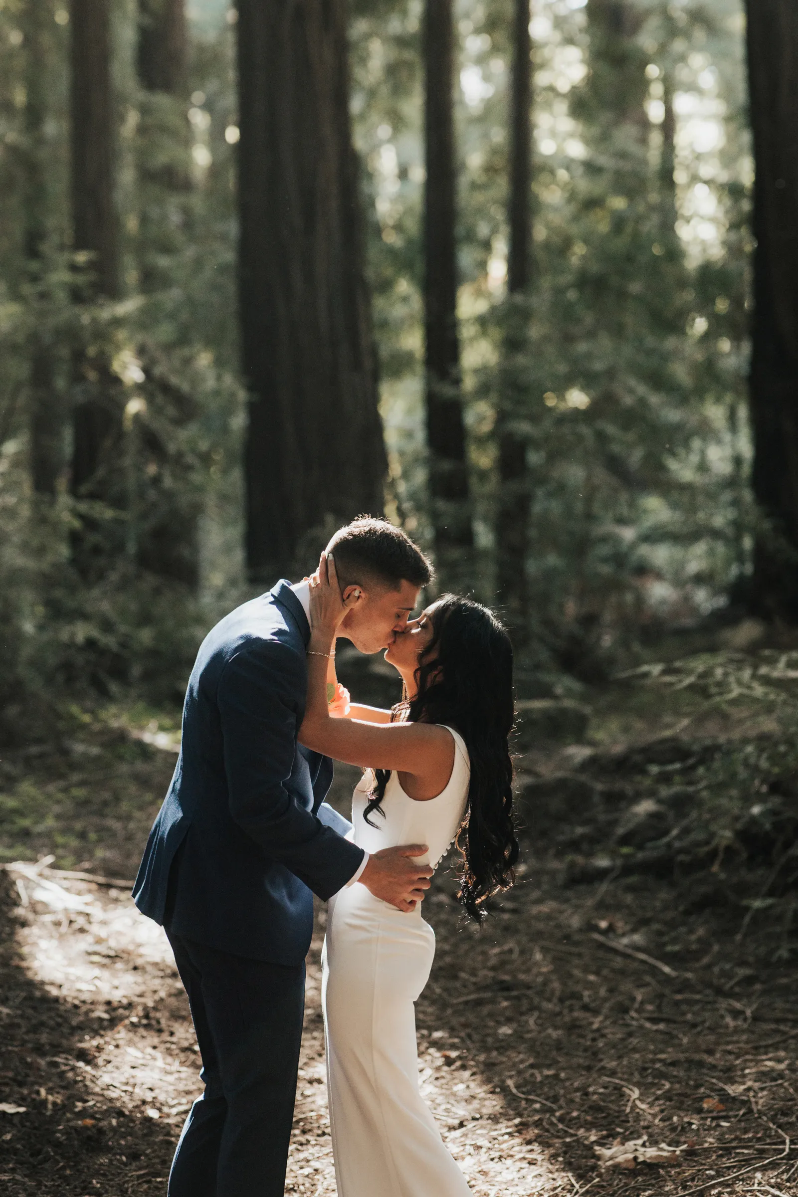 Bride and groom kissing during their ceremony in the woods.