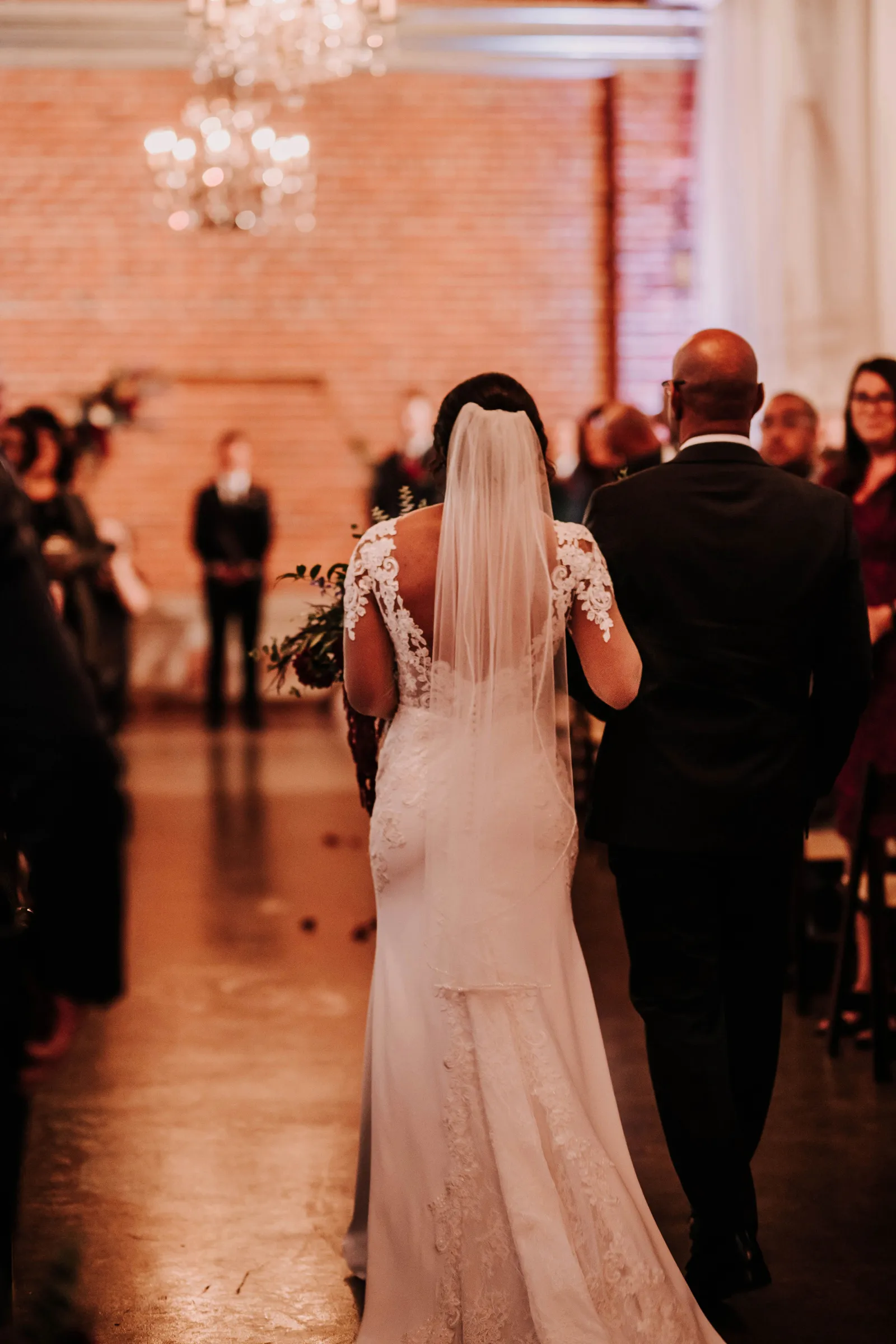 The back of a father walking his daughter down the aisle.