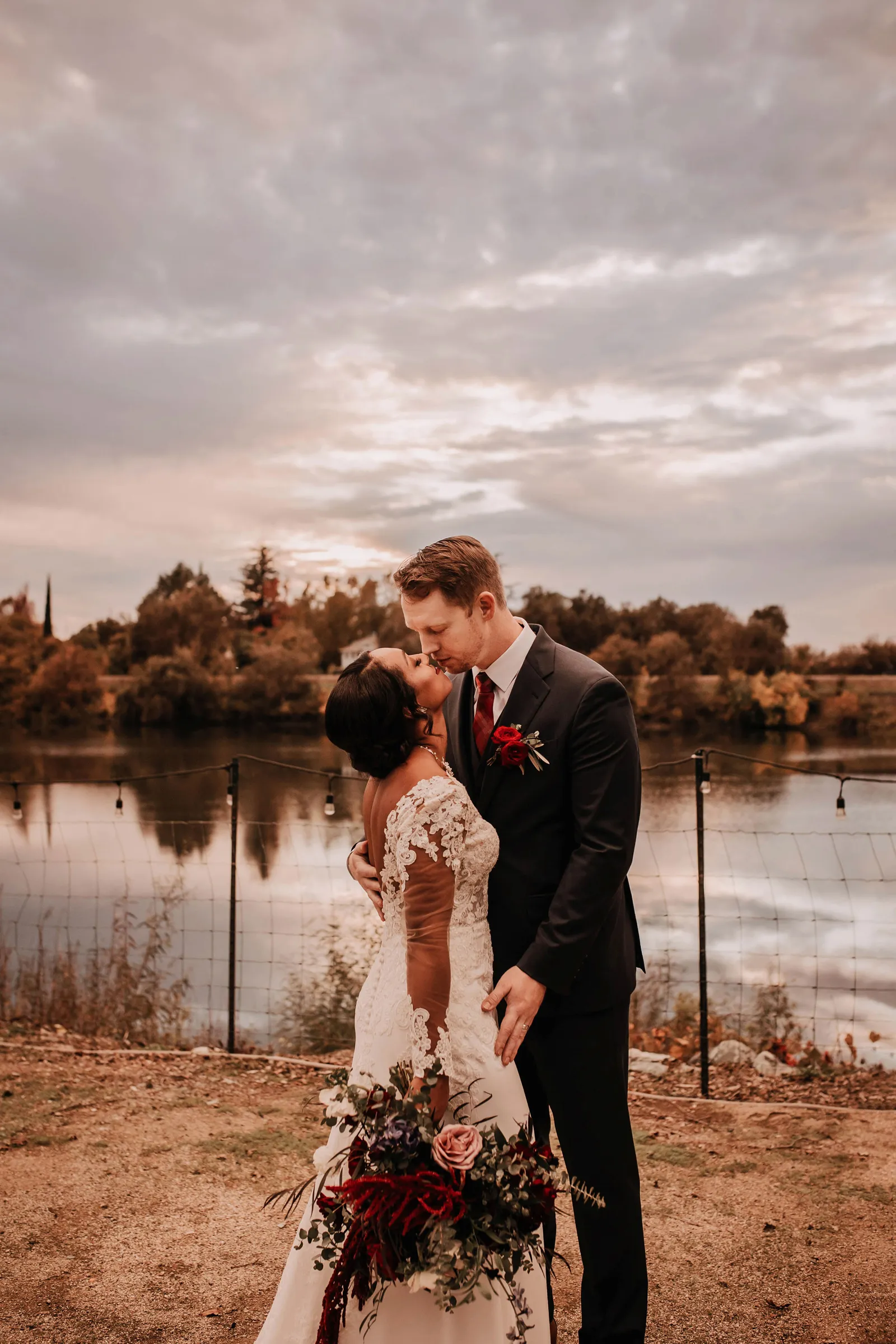 Groom about to kiss his bride by a lake.