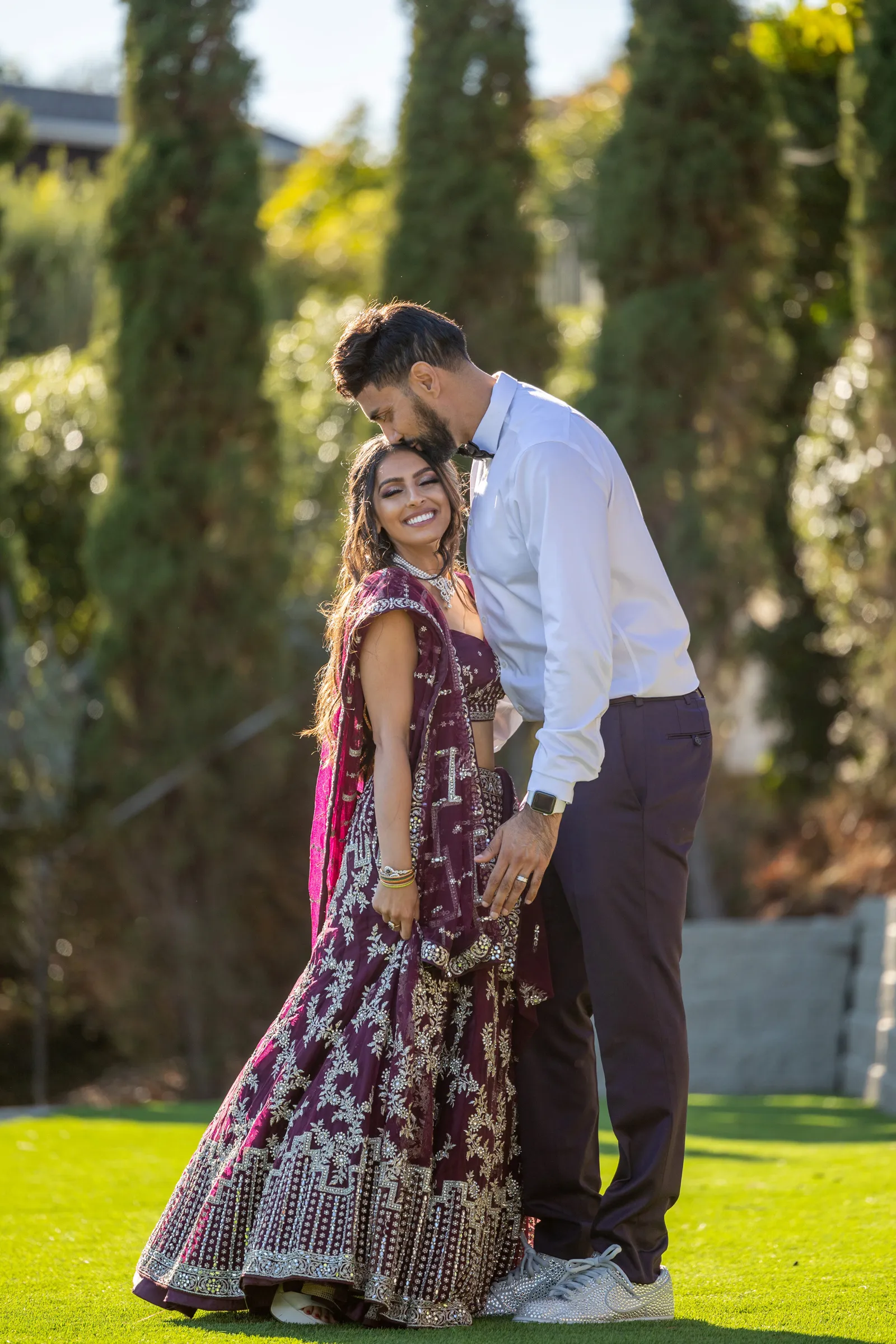 Groom kissing his bride on the head in the backyard.