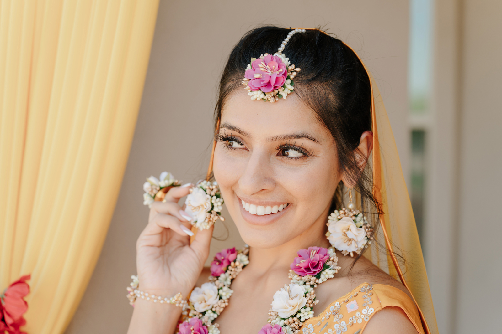 Bride wearing a new traditional Indian wedding gown, sash, and veil smiling.