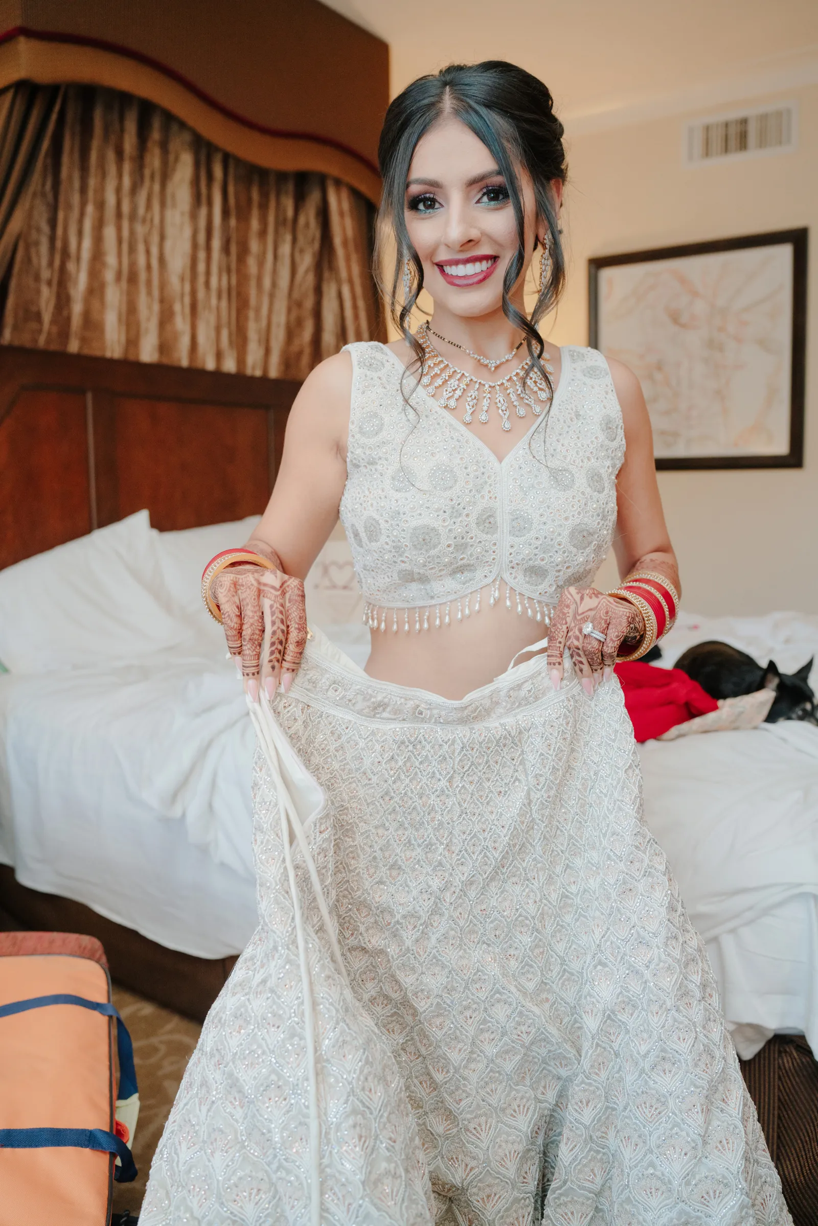 Bride holding her final white gown, and smiling at the camera.