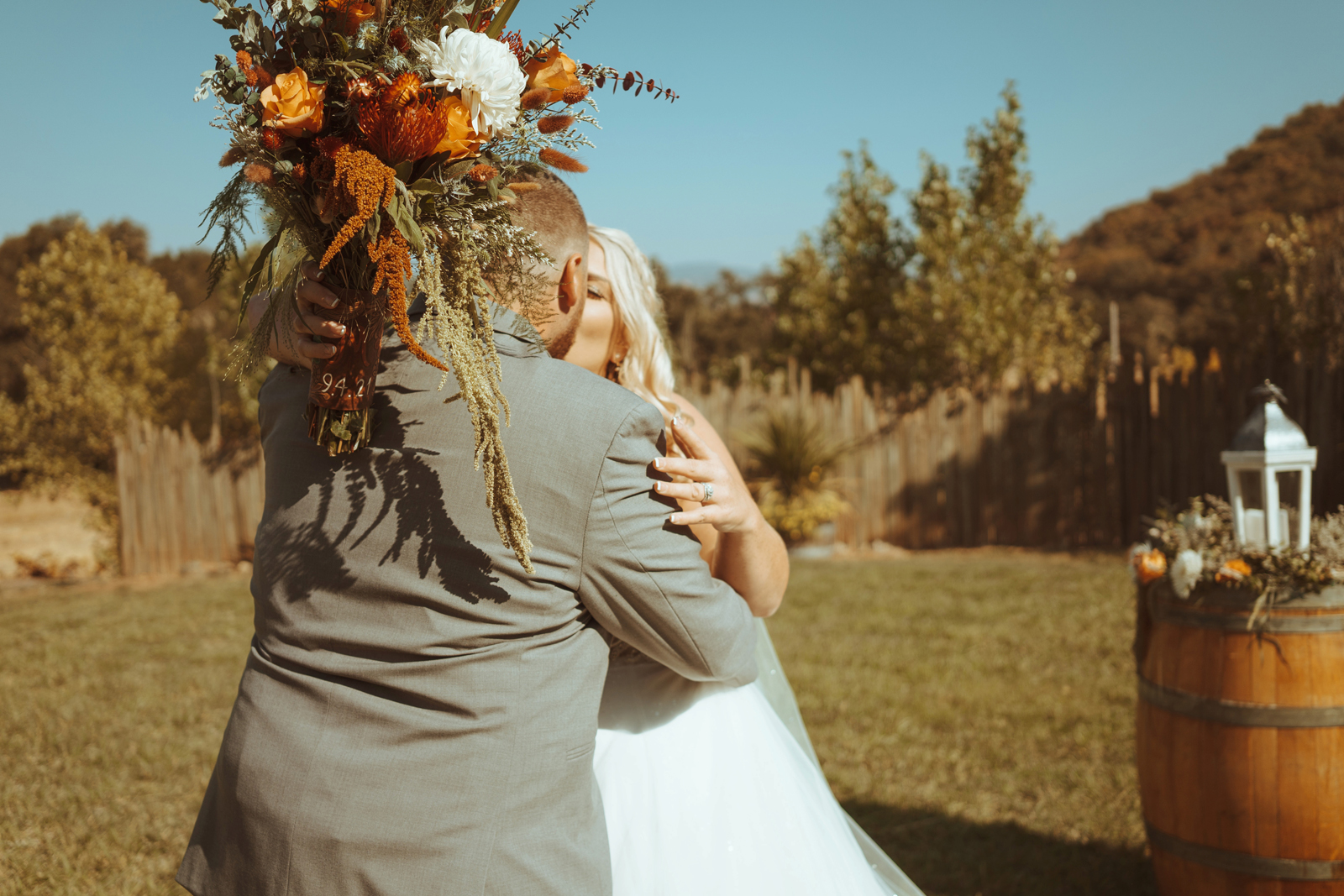 Bride and groom kissing as bride holds her bouquet held up.