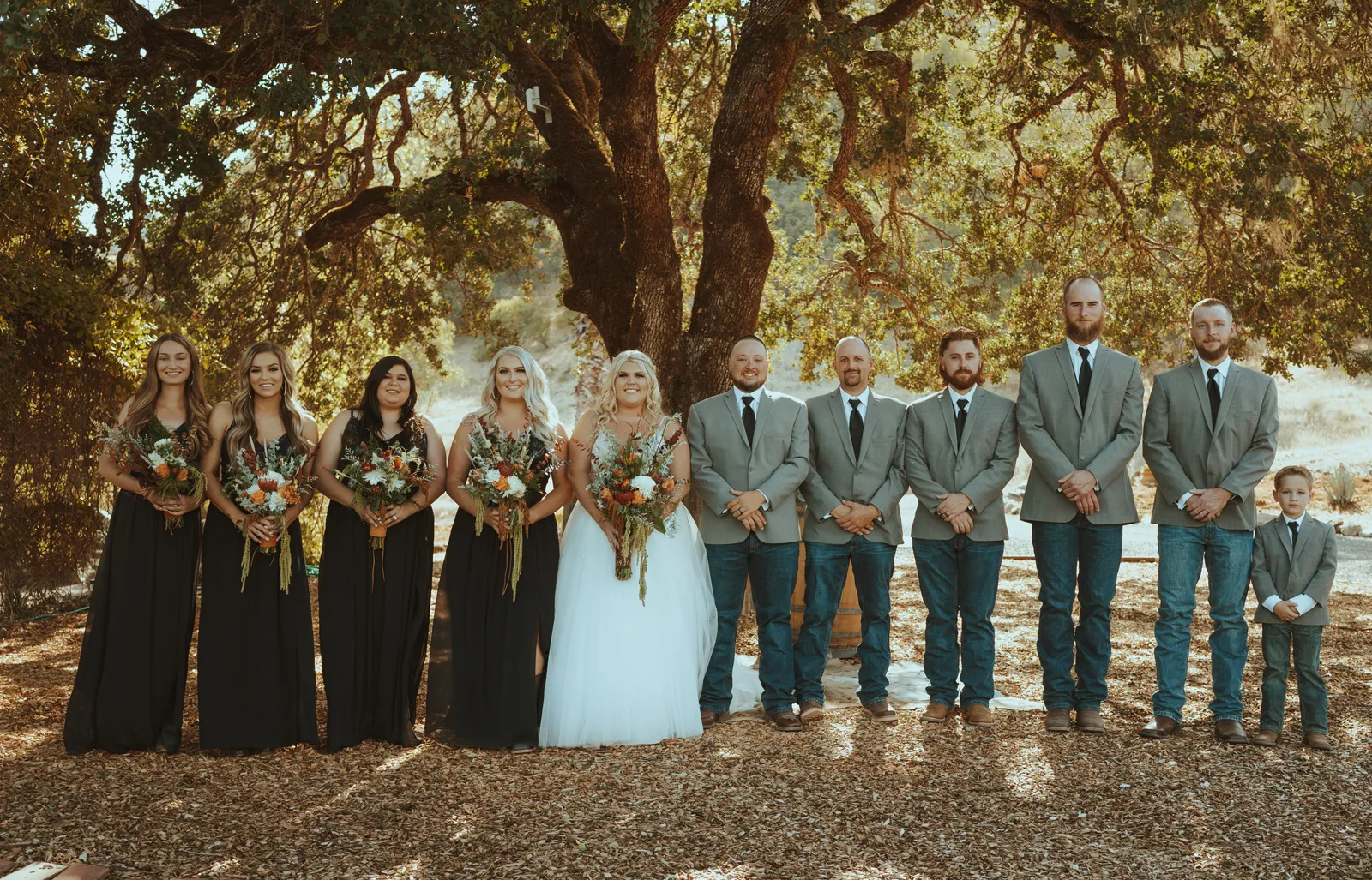 Bride and groom smiling for photos with both of their wedding parties.