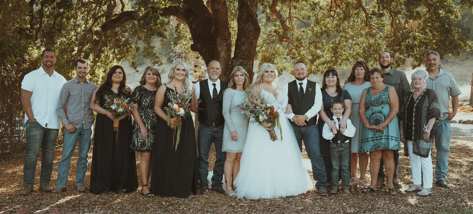 Bride and groom smiling for photos with their whole family.