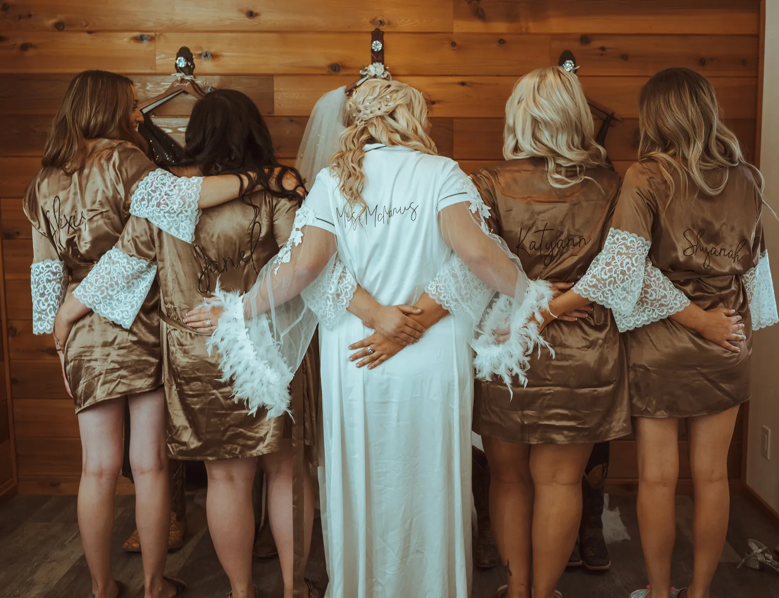 Bride and bridesmaids hugging each other from the back for a photo.