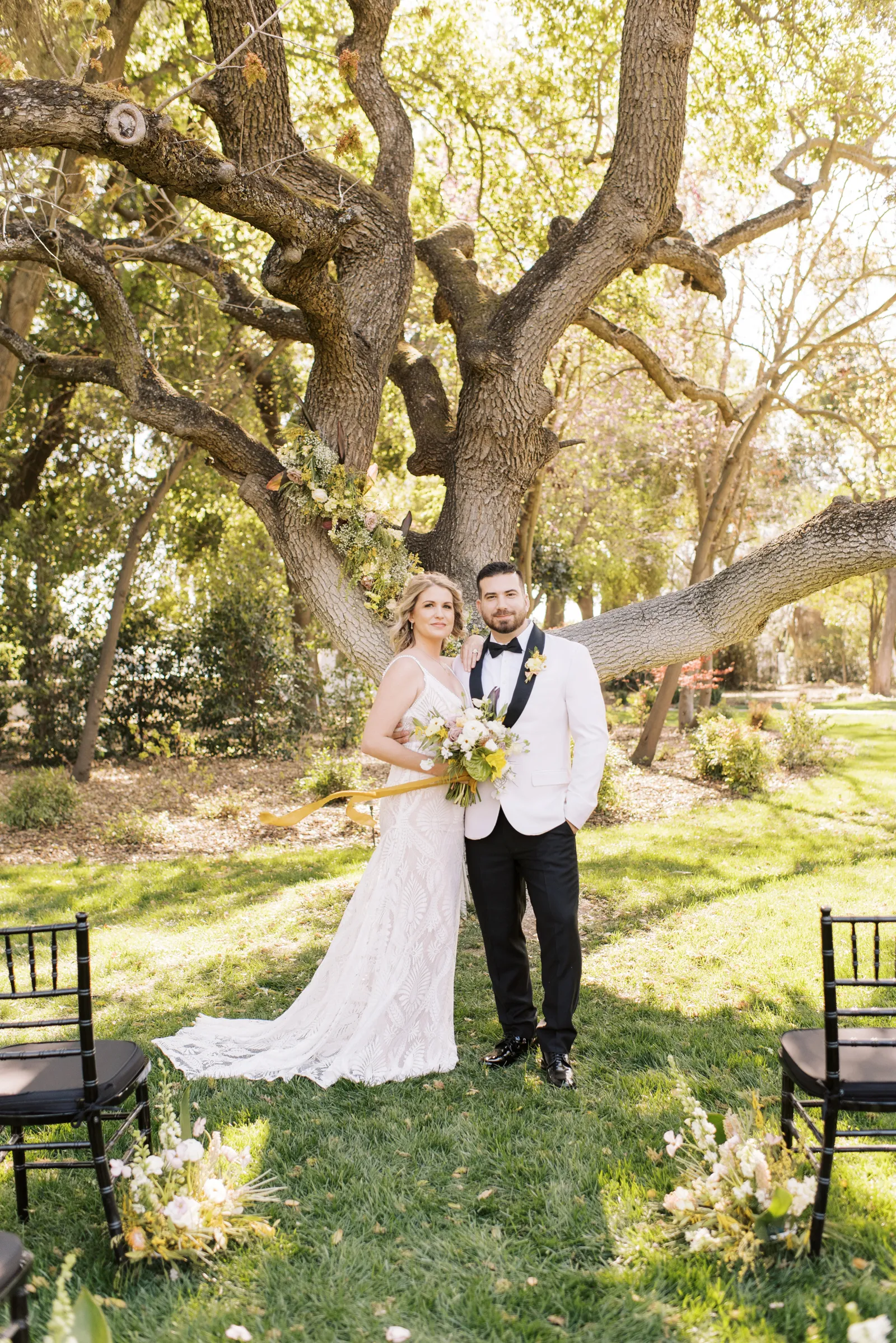 Bride and groom smiling at the end of the aisle outside.