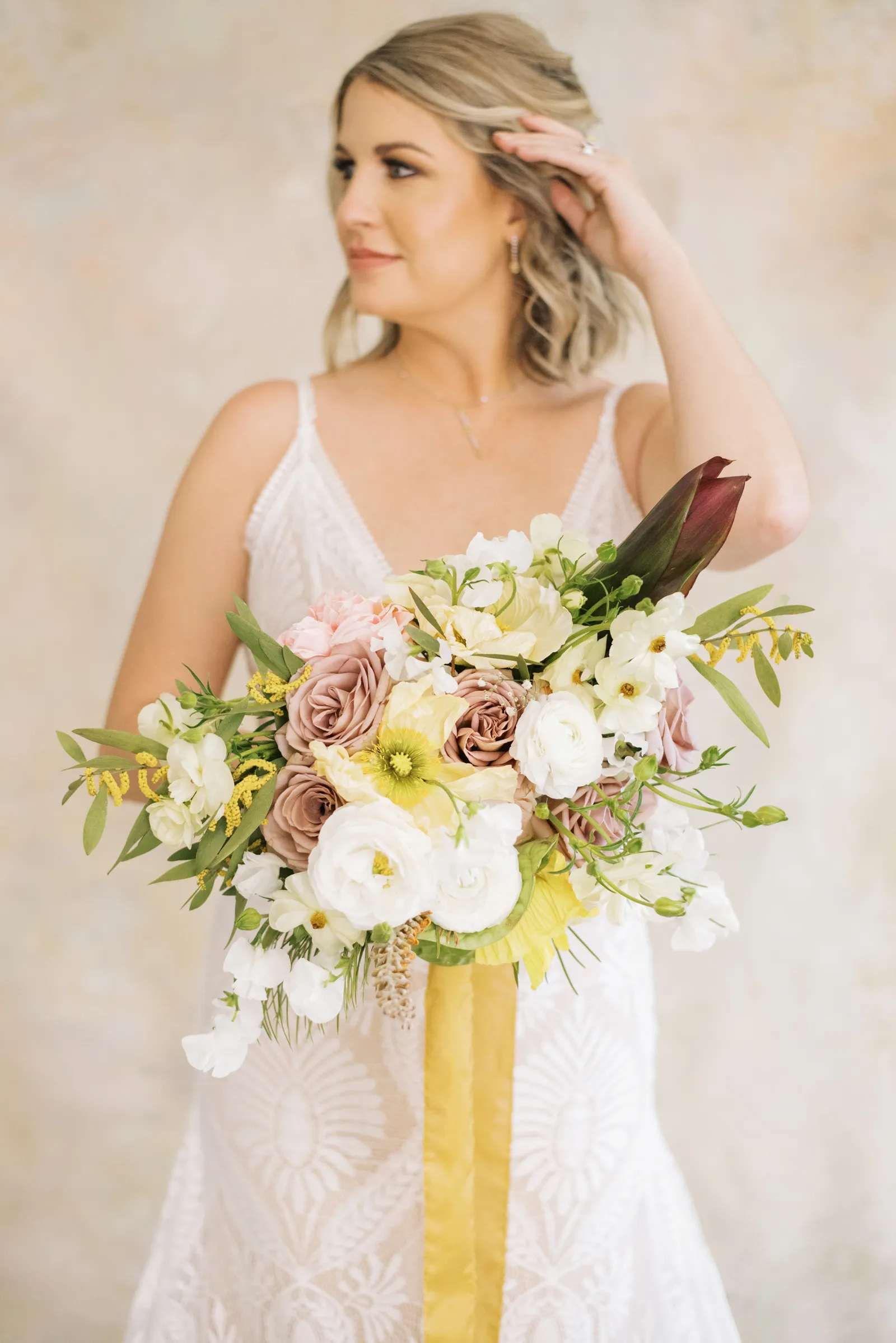 Bride holding her flowers to the camera and looking to the side.