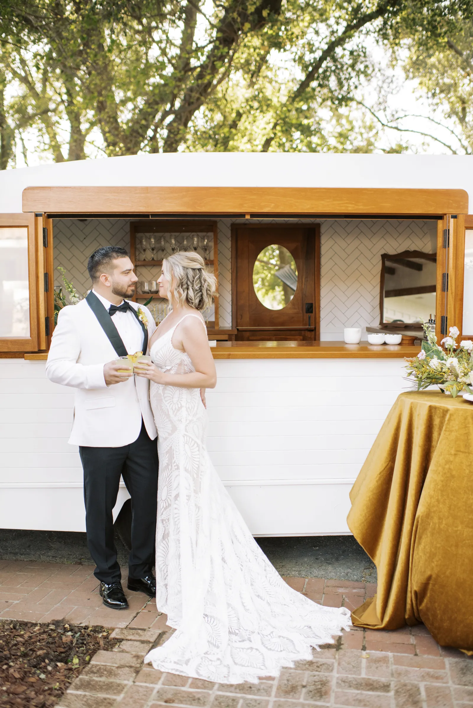 Bride and groom smiling at each other by the mobile bar.