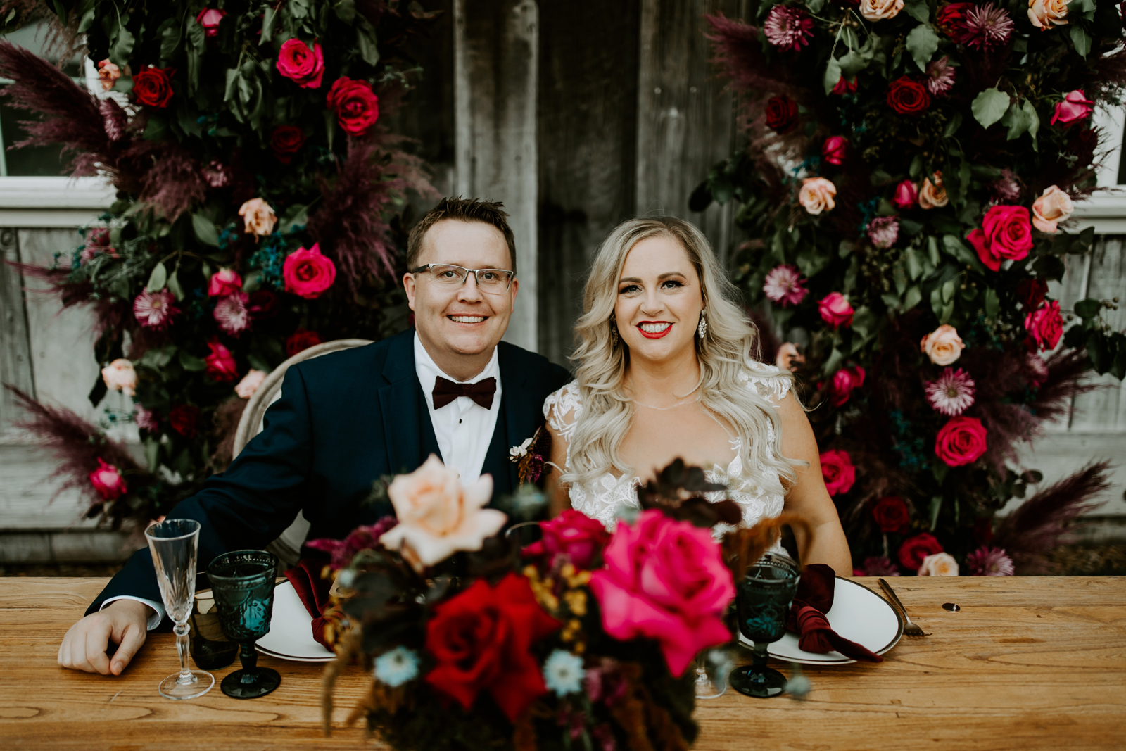 Newlyweds smiling at their couples' table at the reception.