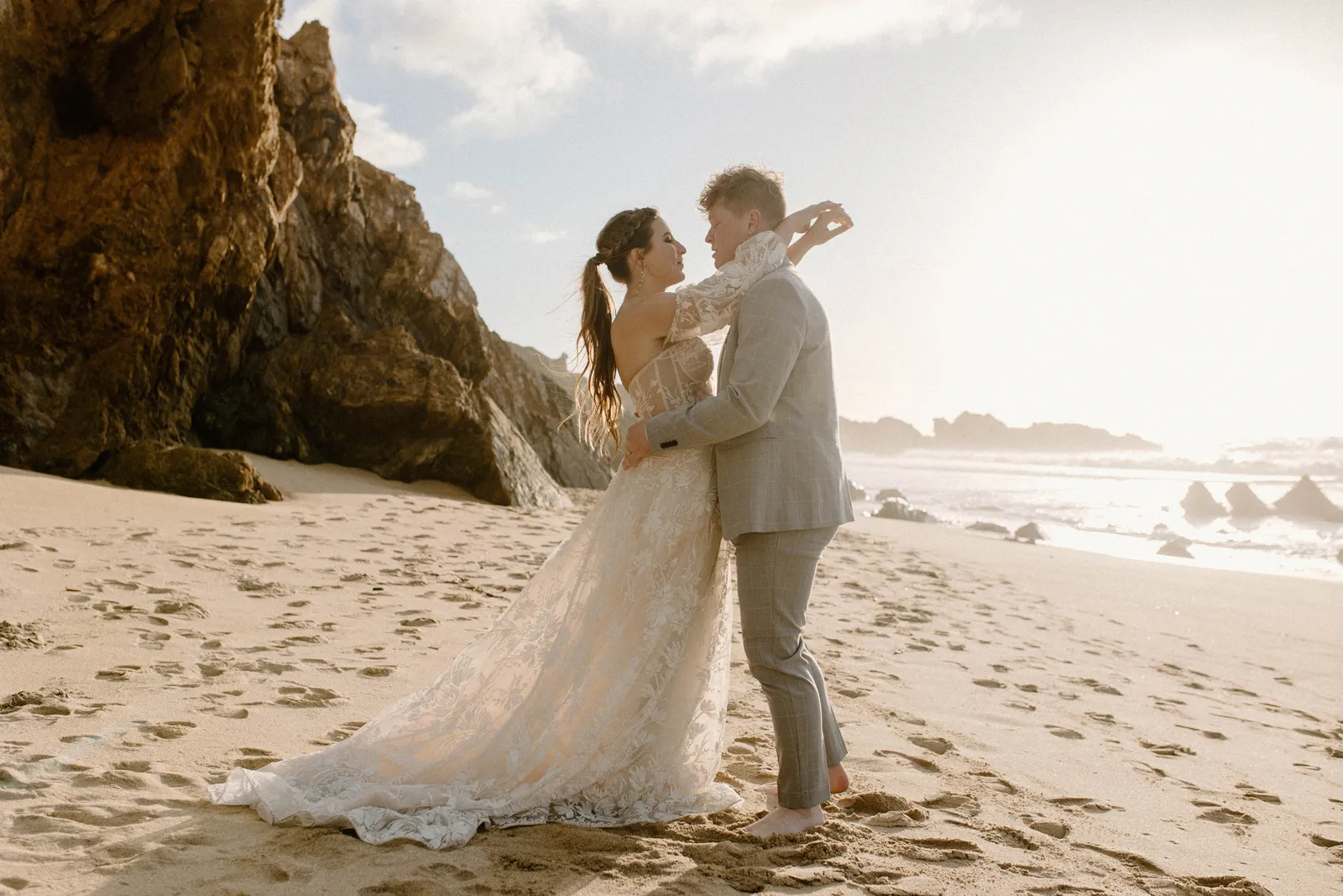 Bride resting her arms over her husband's shoulders at the beach.