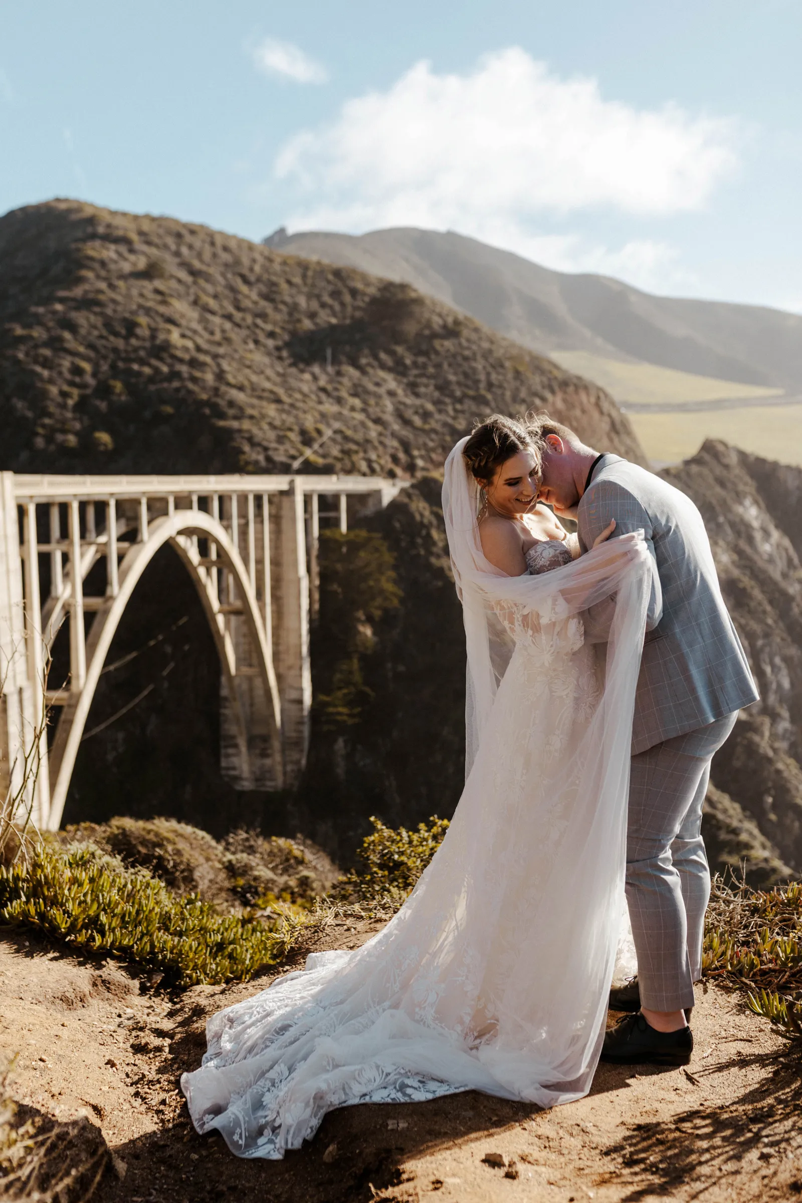 Groom kissing his bride on the neck near the Monterey Bridge.