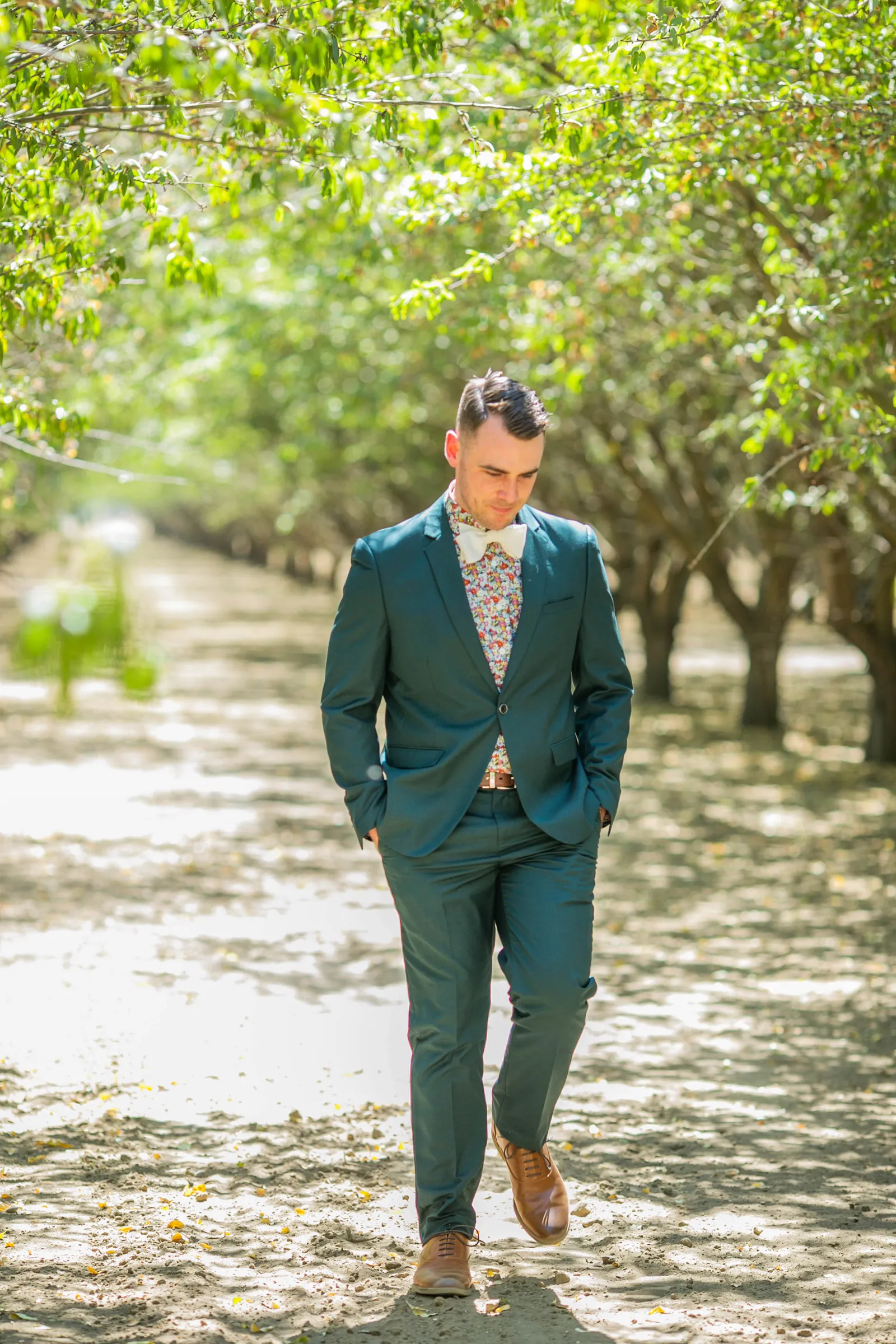 Groom wearing all green tuxedo, walking to meet his bride for a first look.