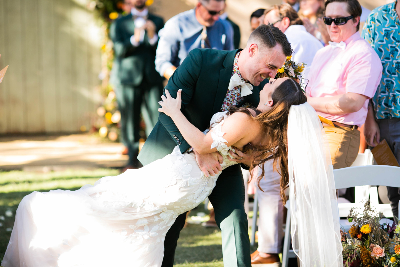 Groom dipping his new bride and kissing her at the end of the aisle.