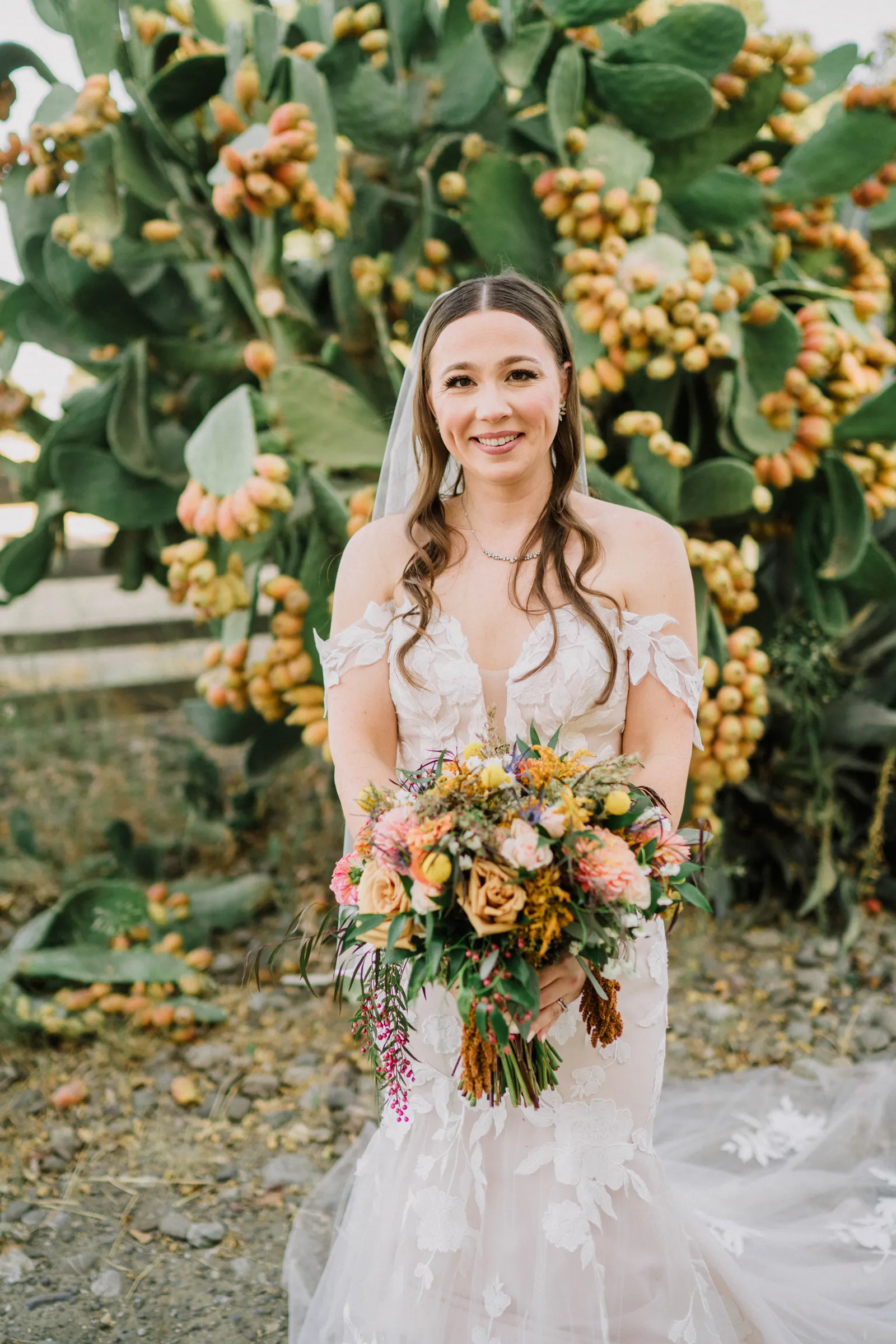 Bride holding her flowers in front of a large fruit tree.