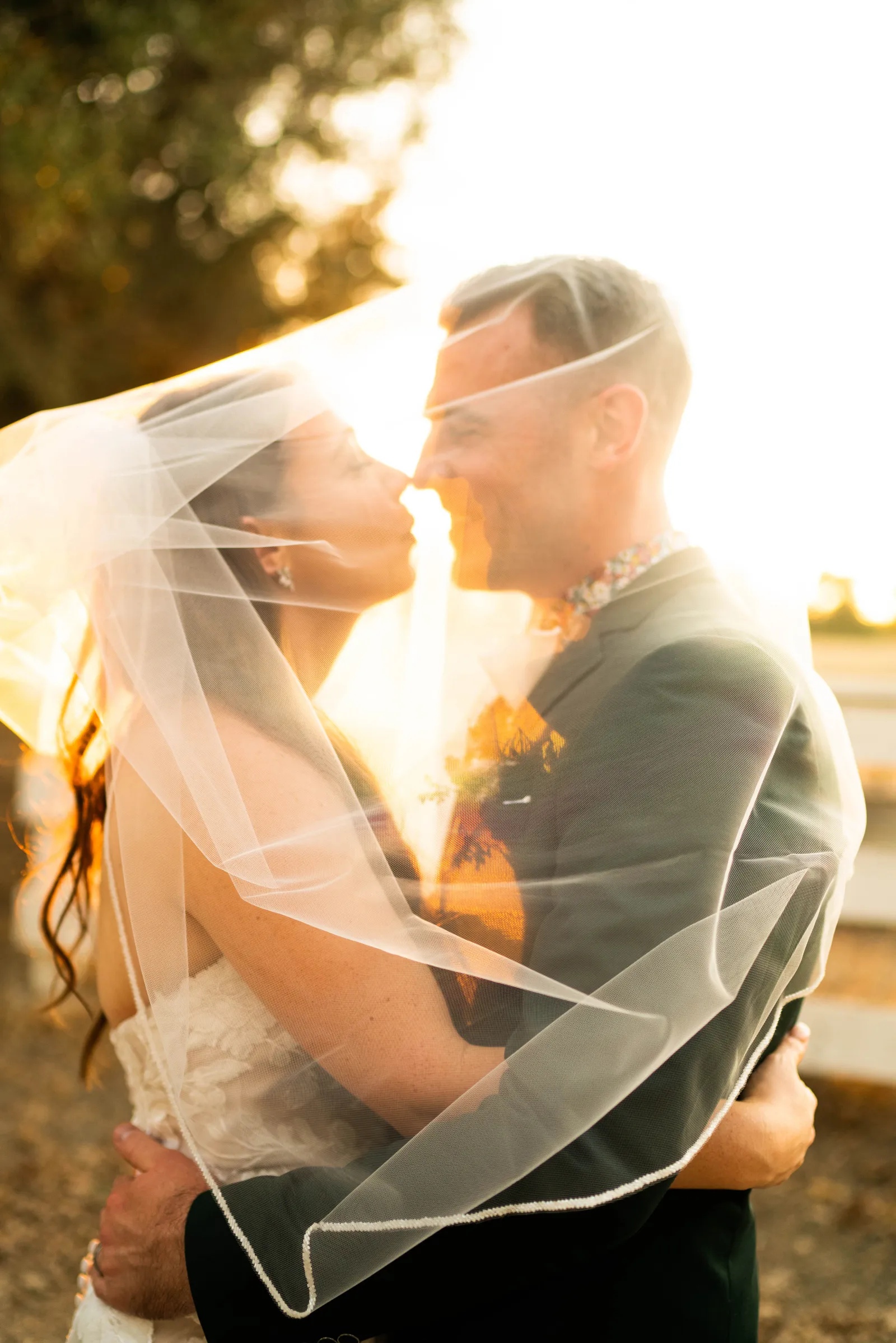 Newlyweds smiling at each other while the brides veil wraps around them.