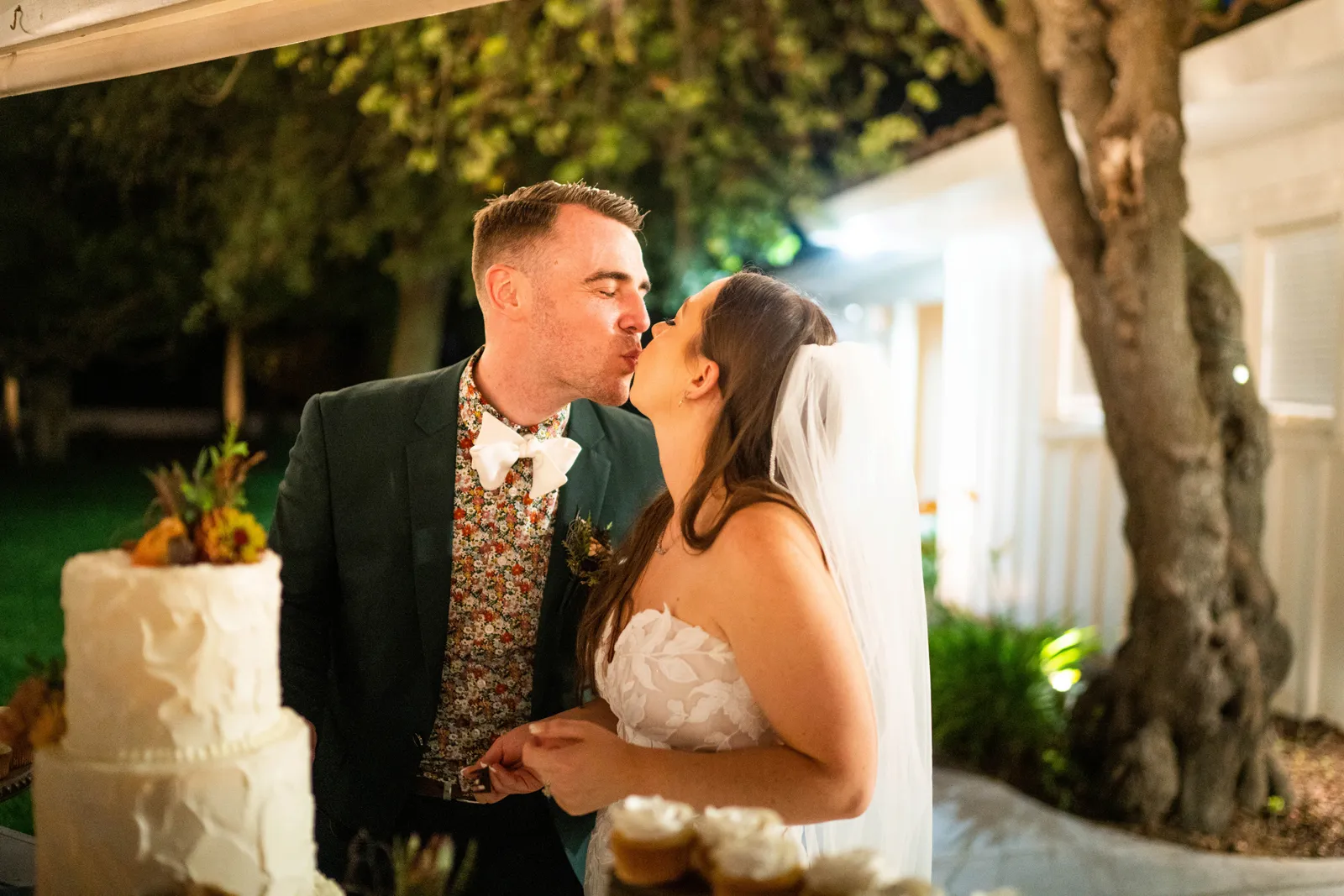 Bride and groom kissing after sharing cake.