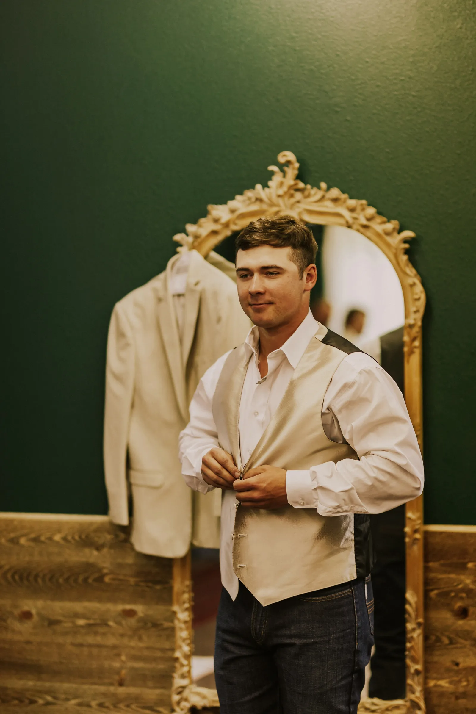 Groom getting ready for his wedding and buttoning his vest.