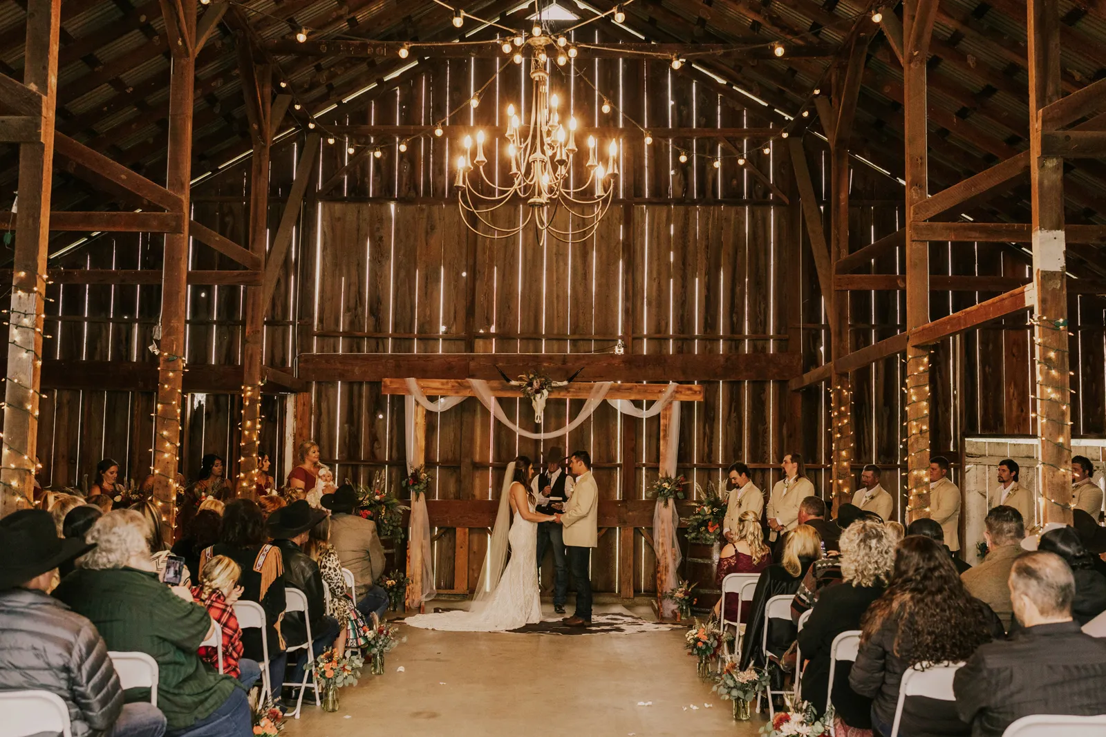 Bride and groom holding hands inside their barn venue.